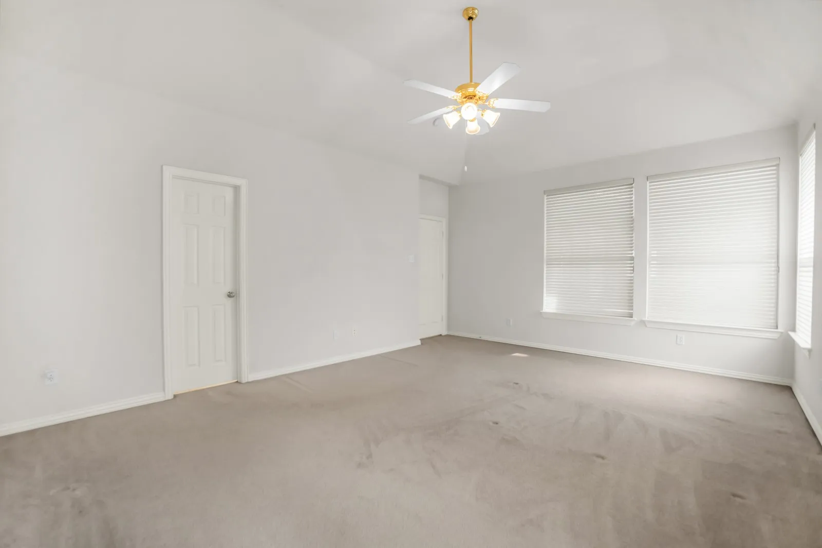 Carpeted empty room featuring ceiling fan, lofted ceiling, and healthy amount of natural light