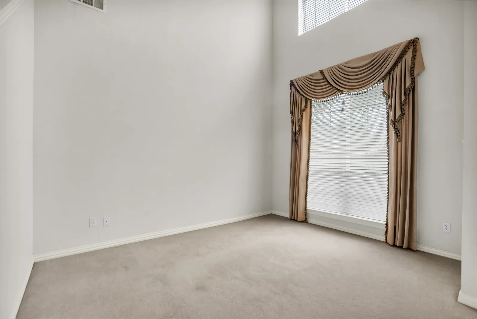Empty room featuring light colored carpet and a high ceiling