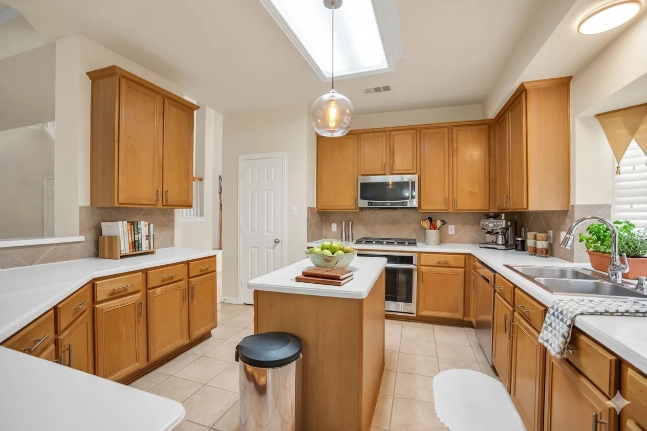 Kitchen with light countertops, a skylight, and light tile patterned flooring