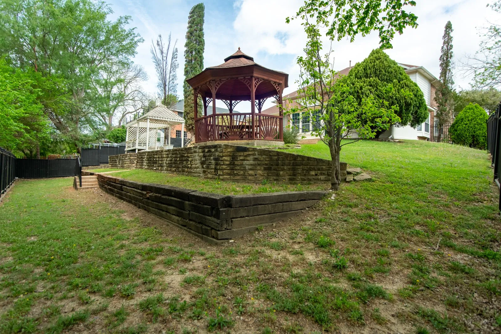 Fenced backyard featuring a gazebo and a deck