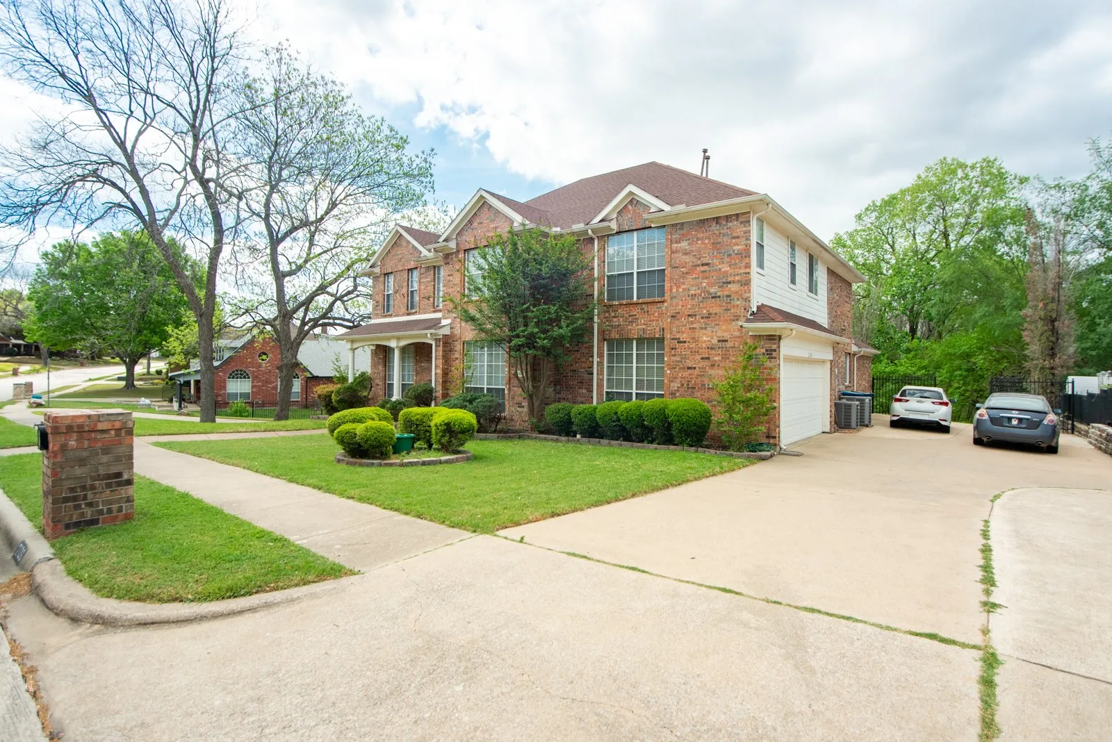 Traditional home with driveway, a garage, brick siding, and a front lawn