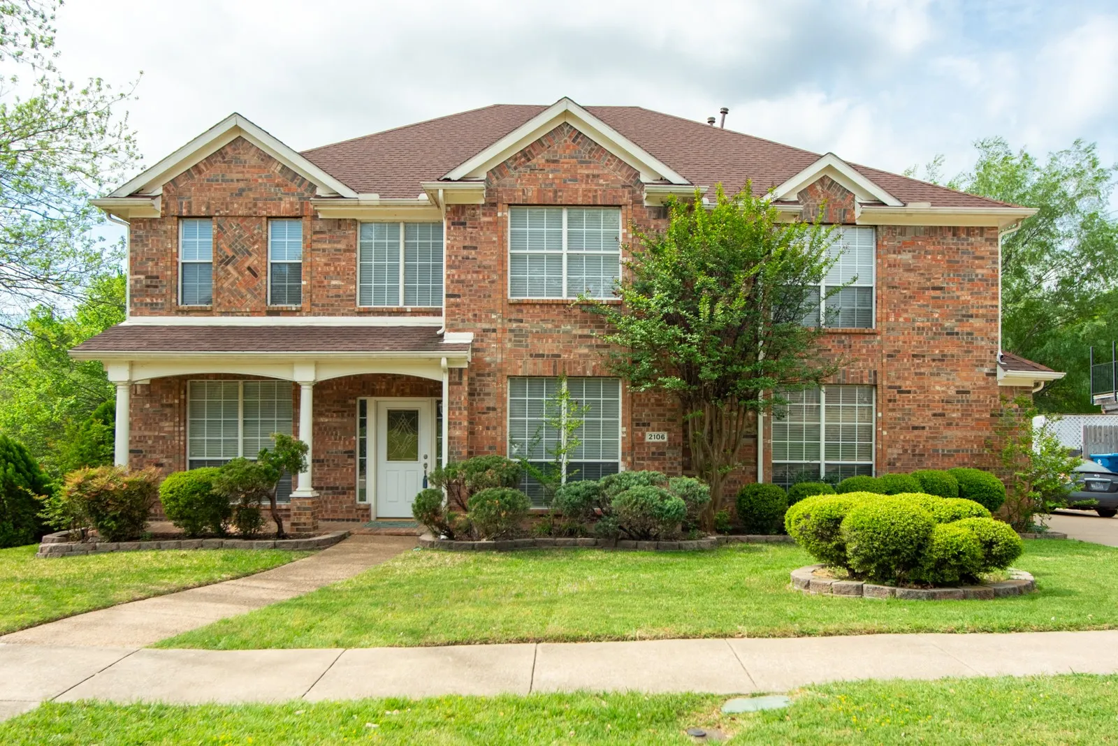 Traditional-style house featuring a front lawn, brick siding, and a porch