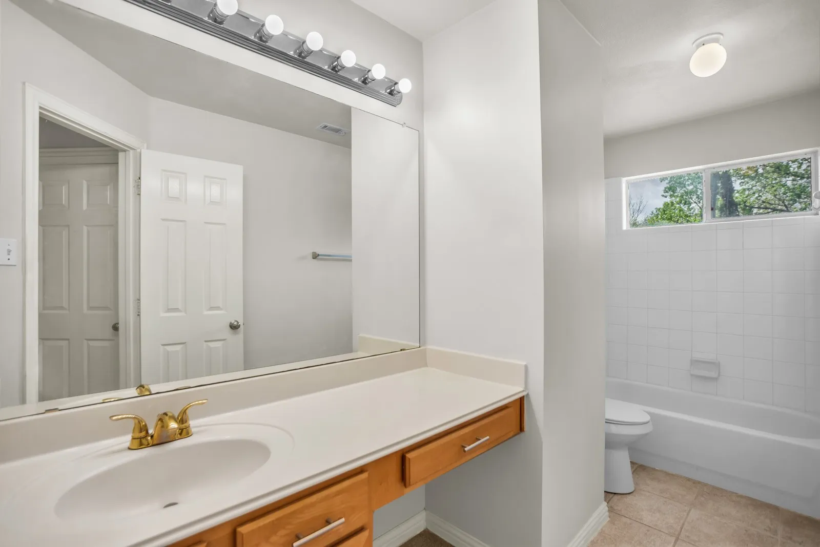 Bathroom featuring vanity, shower / bathtub combination, and light tile patterned flooring