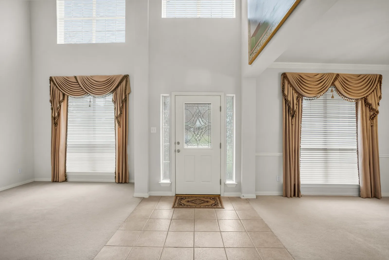 Entrance foyer with light carpet, light tile patterned floors, plenty of natural light, and a high ceiling