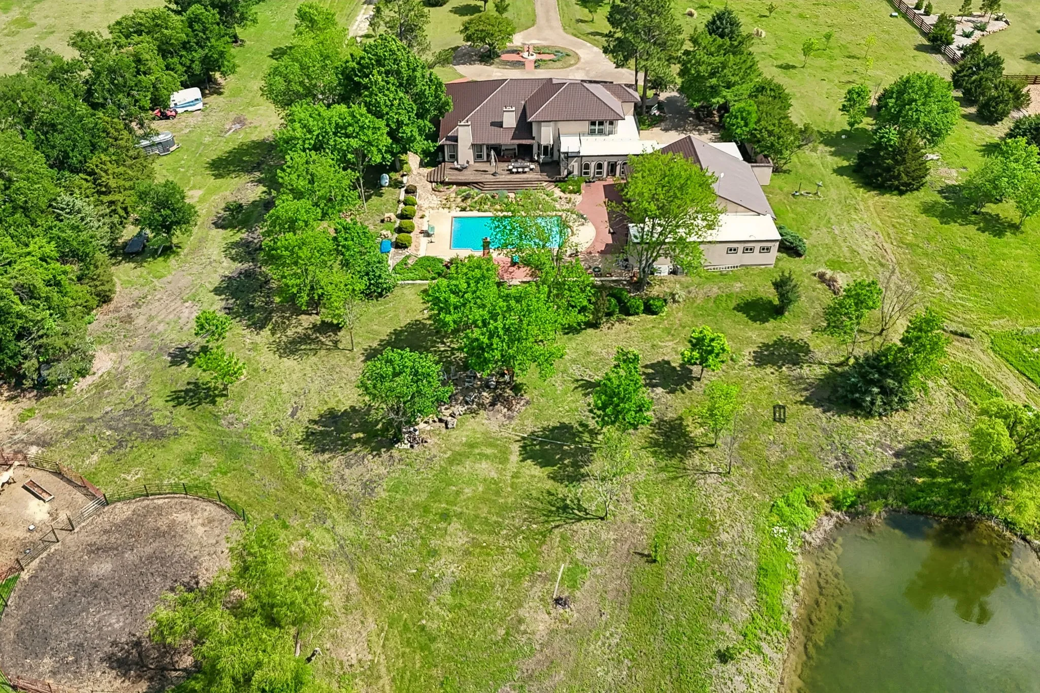 Expansive property featuring a multi-level residence with a metal roof, a rectangular swimming pool with surrounding brick paving