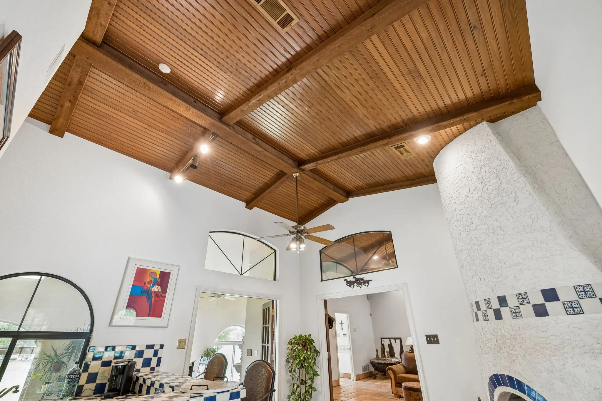 Vaulted wood-planked ceiling with exposed beams and recessed lighting
