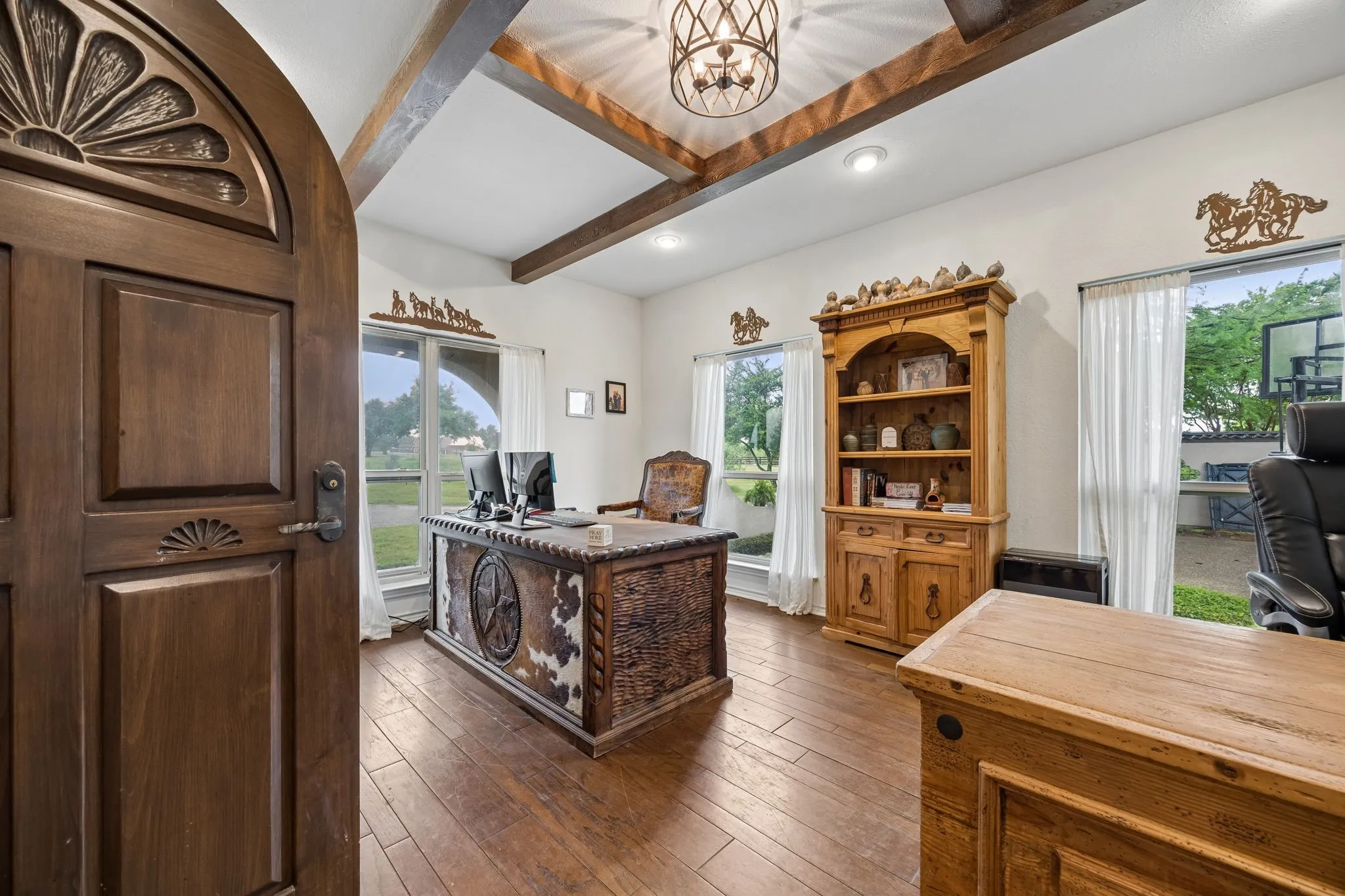Interior space with wood-finish flooring, exposed ceiling beams, and a decorative ceiling light fixture