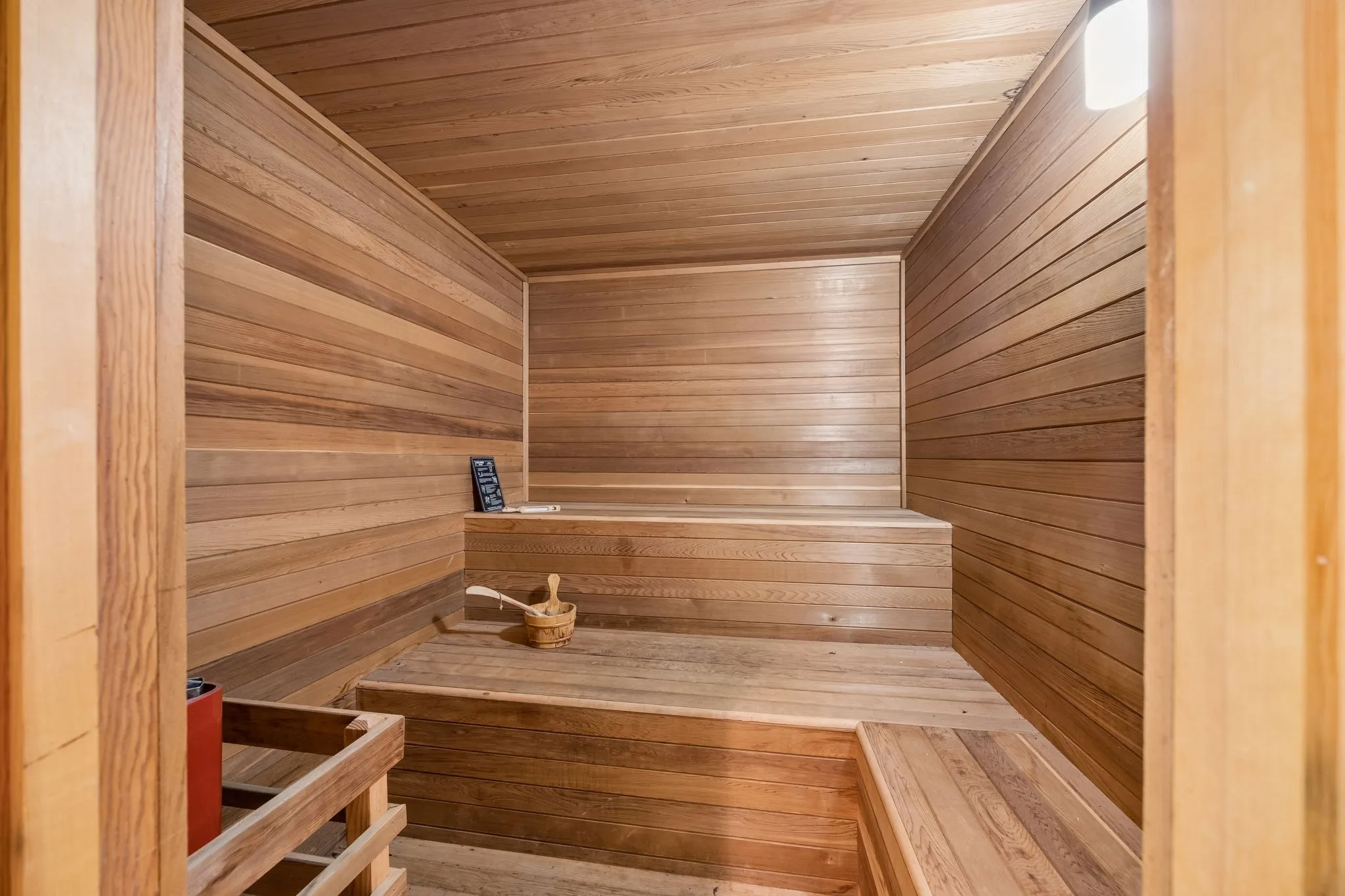 Wood-paneled sauna featuring tiered wooden benches and a built-in heater