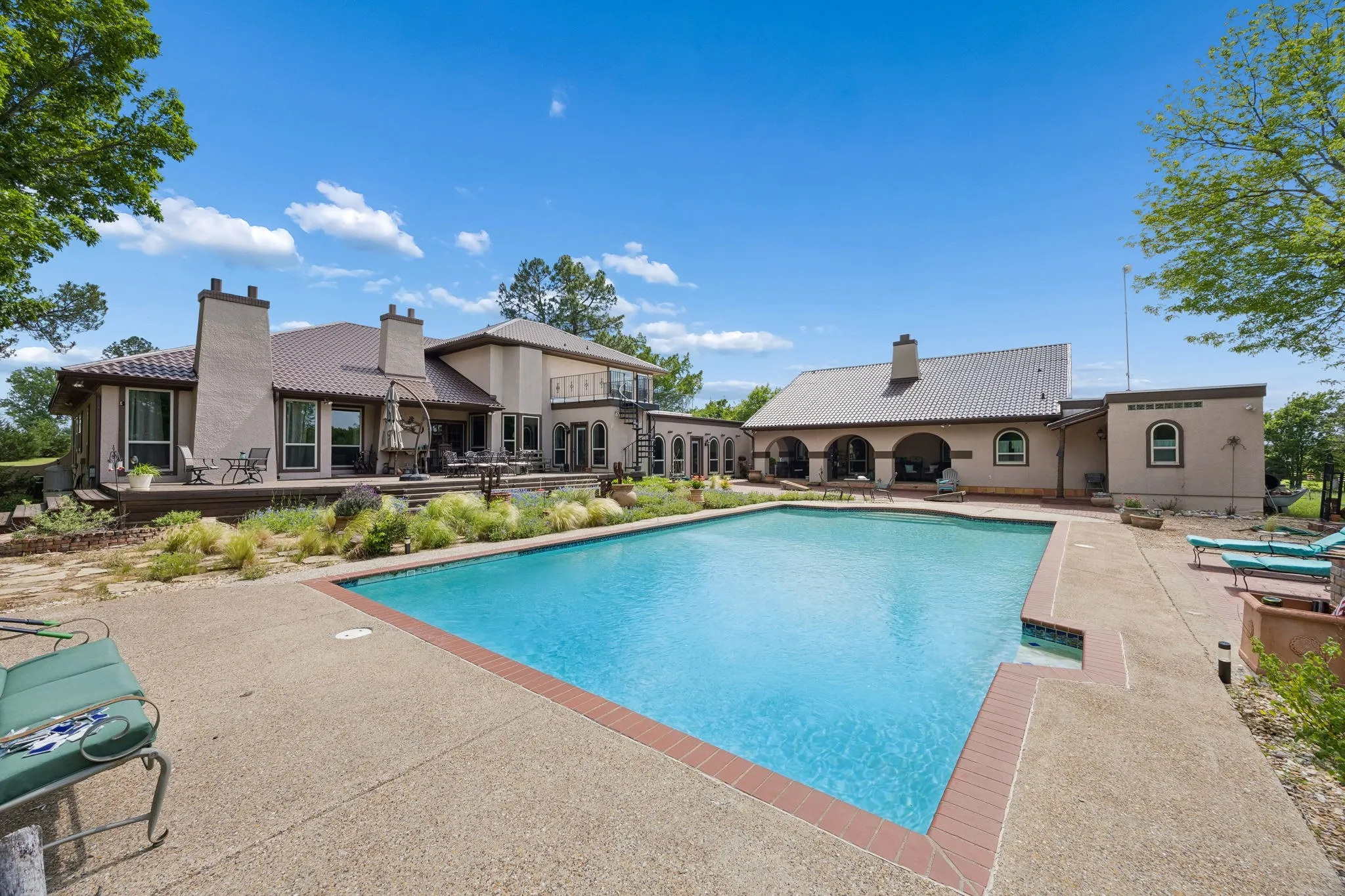 Expansive pool area featuring a large inground swimming pool with integrated spa and surrounding concrete patio