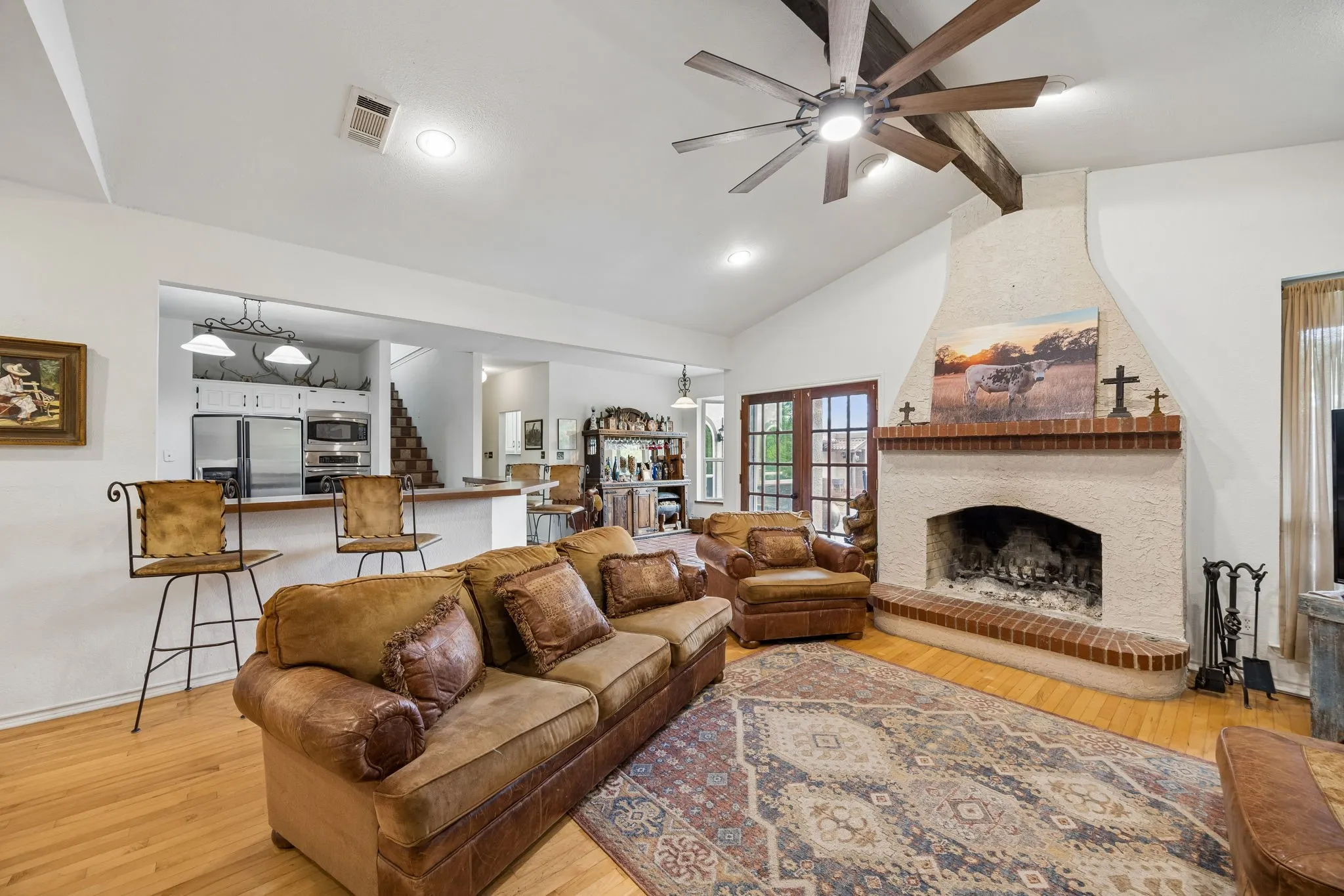 Living room with vaulted ceiling, exposed wood beams, and a ceiling fan