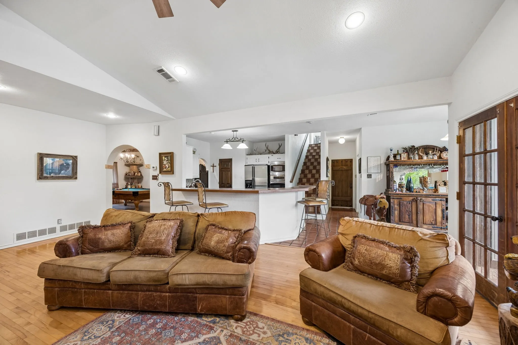 Expansive living area featuring hardwood flooring, recessed lighting, and a vaulted ceiling