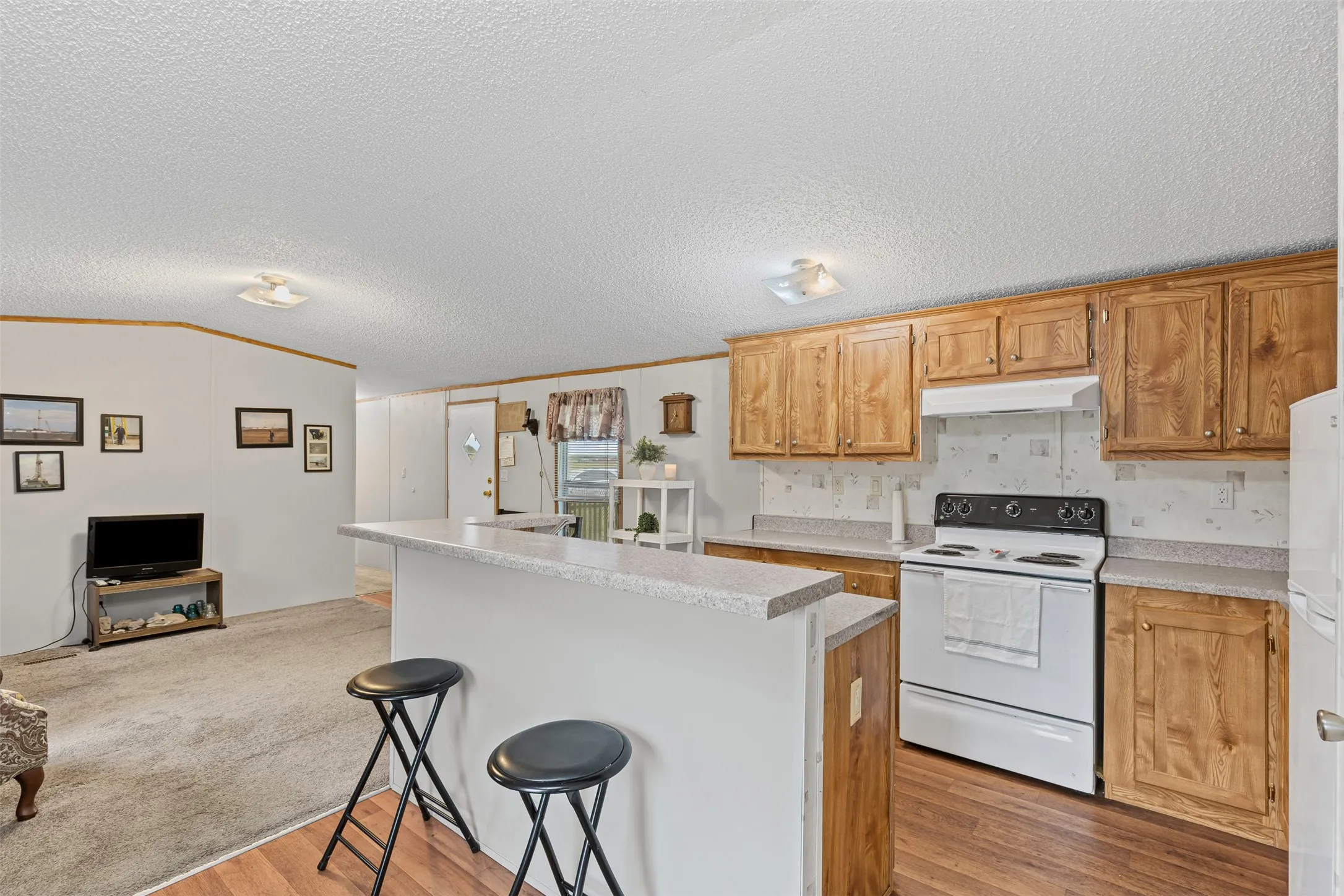 Kitchen featuring white appliances, open floor plan, a breakfast bar area, ornamental molding, and a kitchen island