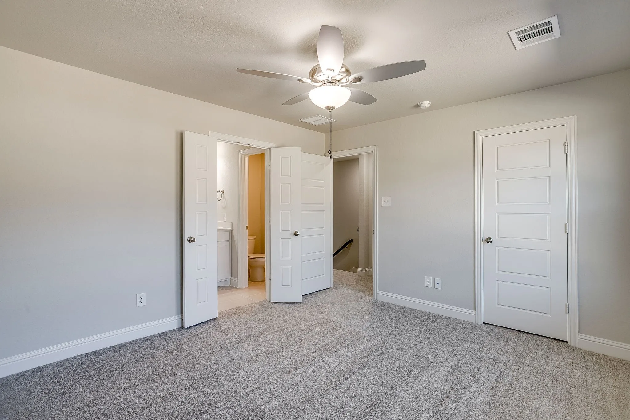 Unfurnished bedroom featuring light colored carpet, ceiling fan, and ensuite bathroom