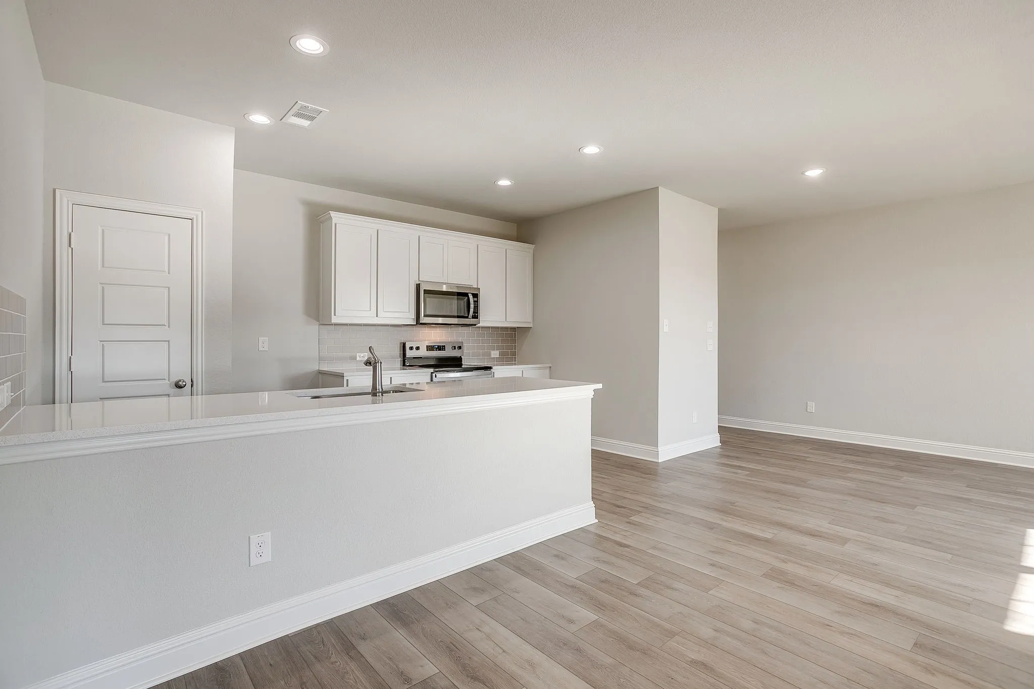 Kitchen with white cabinets, stainless steel appliances, light wood-type flooring, recessed lighting, and light stone countertops
