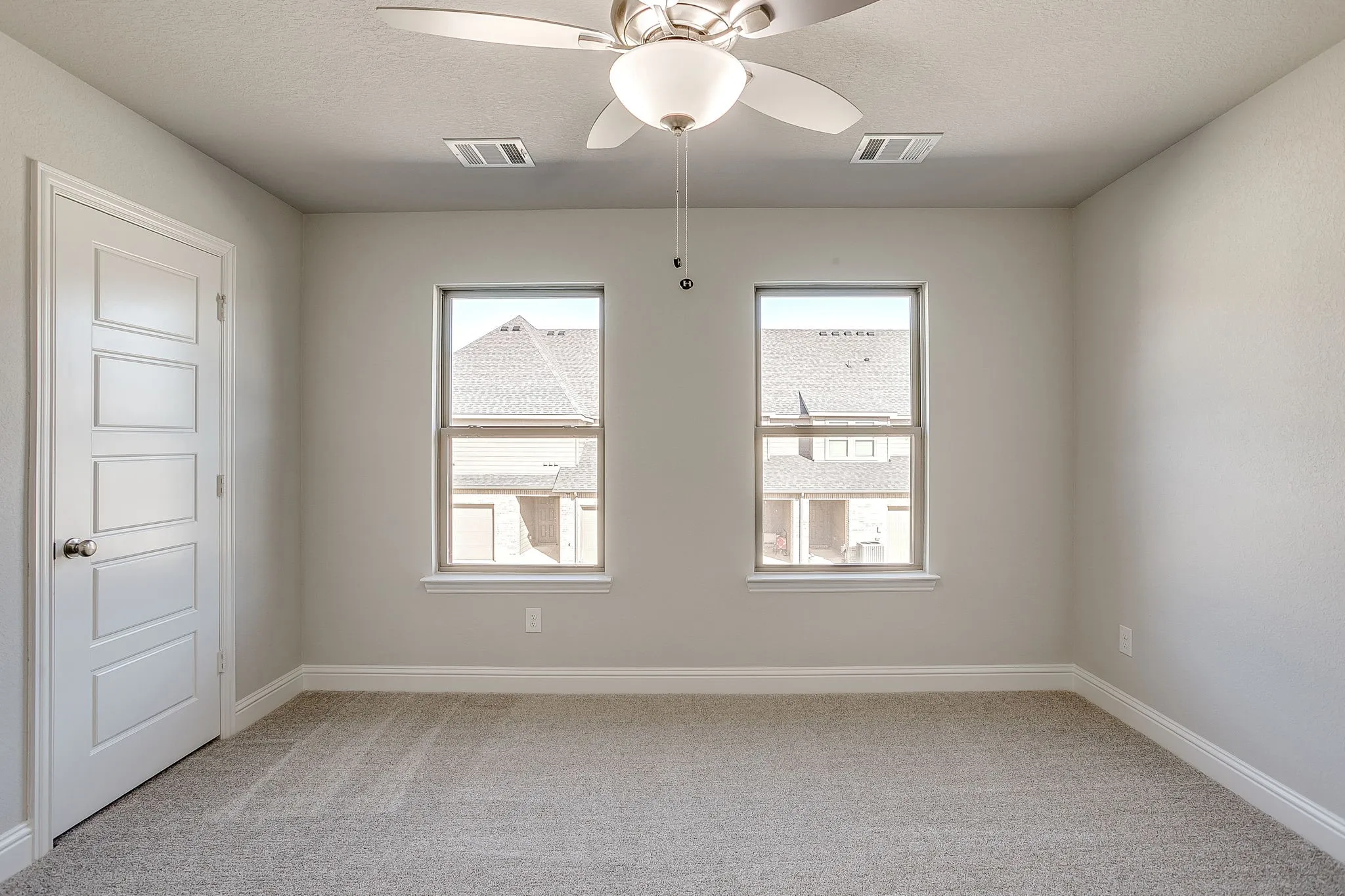 Empty room with a ceiling fan, light carpet, and a textured ceiling