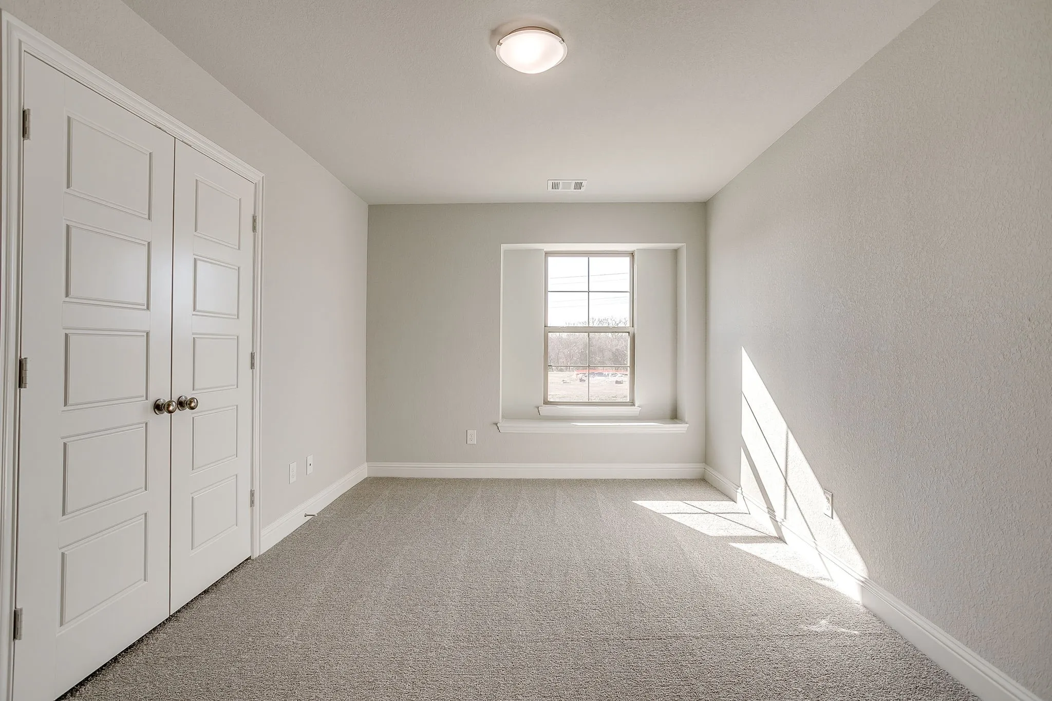 Unfurnished bedroom with light colored carpet and baseboards