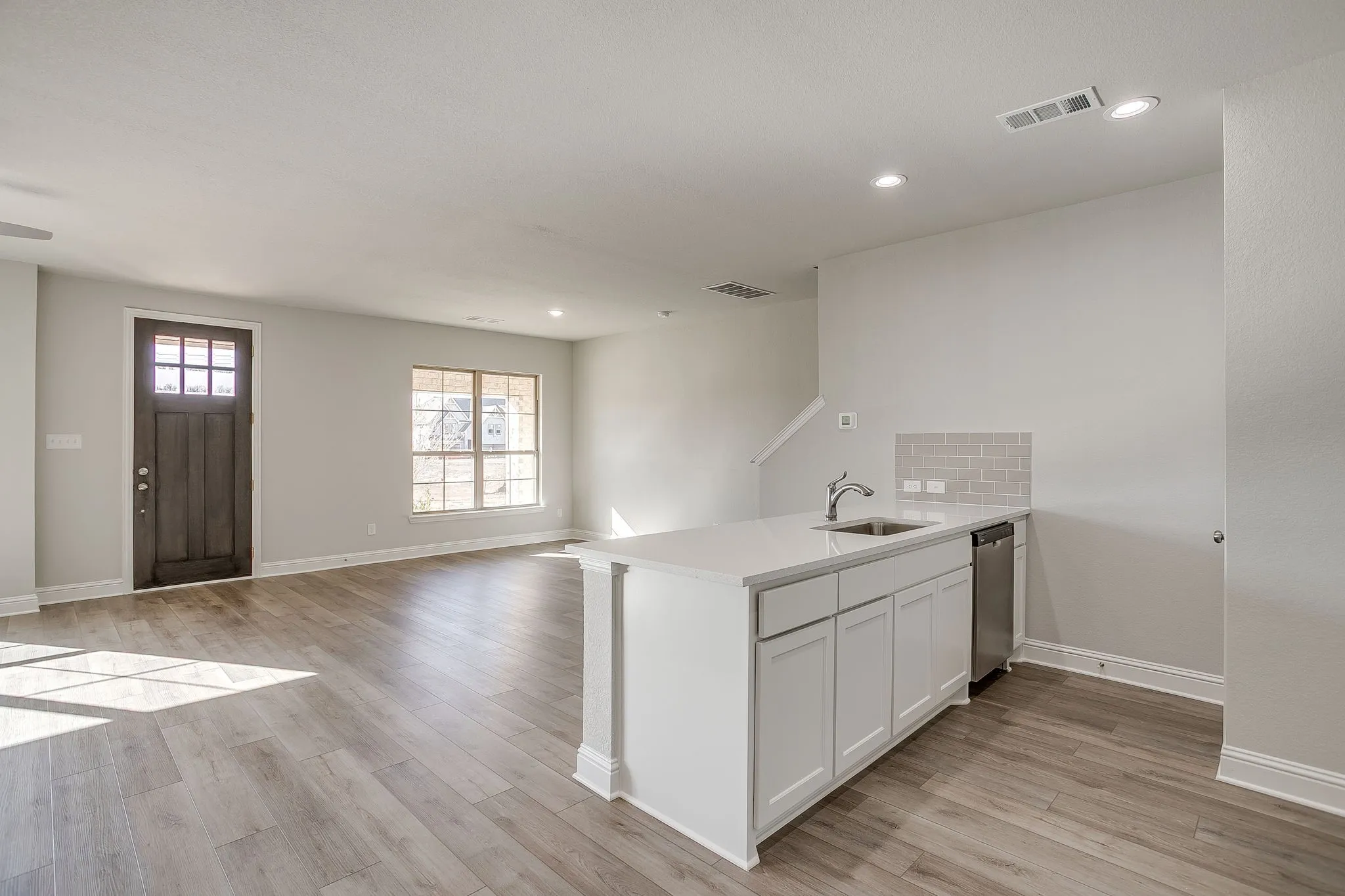 Kitchen featuring a peninsula, open floor plan, light wood-style flooring, white cabinetry, and recessed lighting