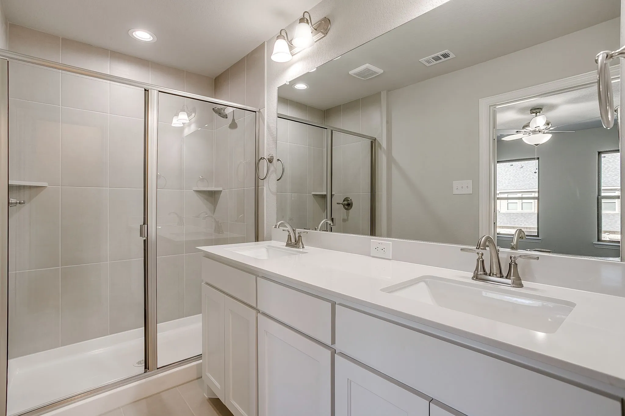 Full bathroom with double vanity, a stall shower, a ceiling fan, and recessed lighting