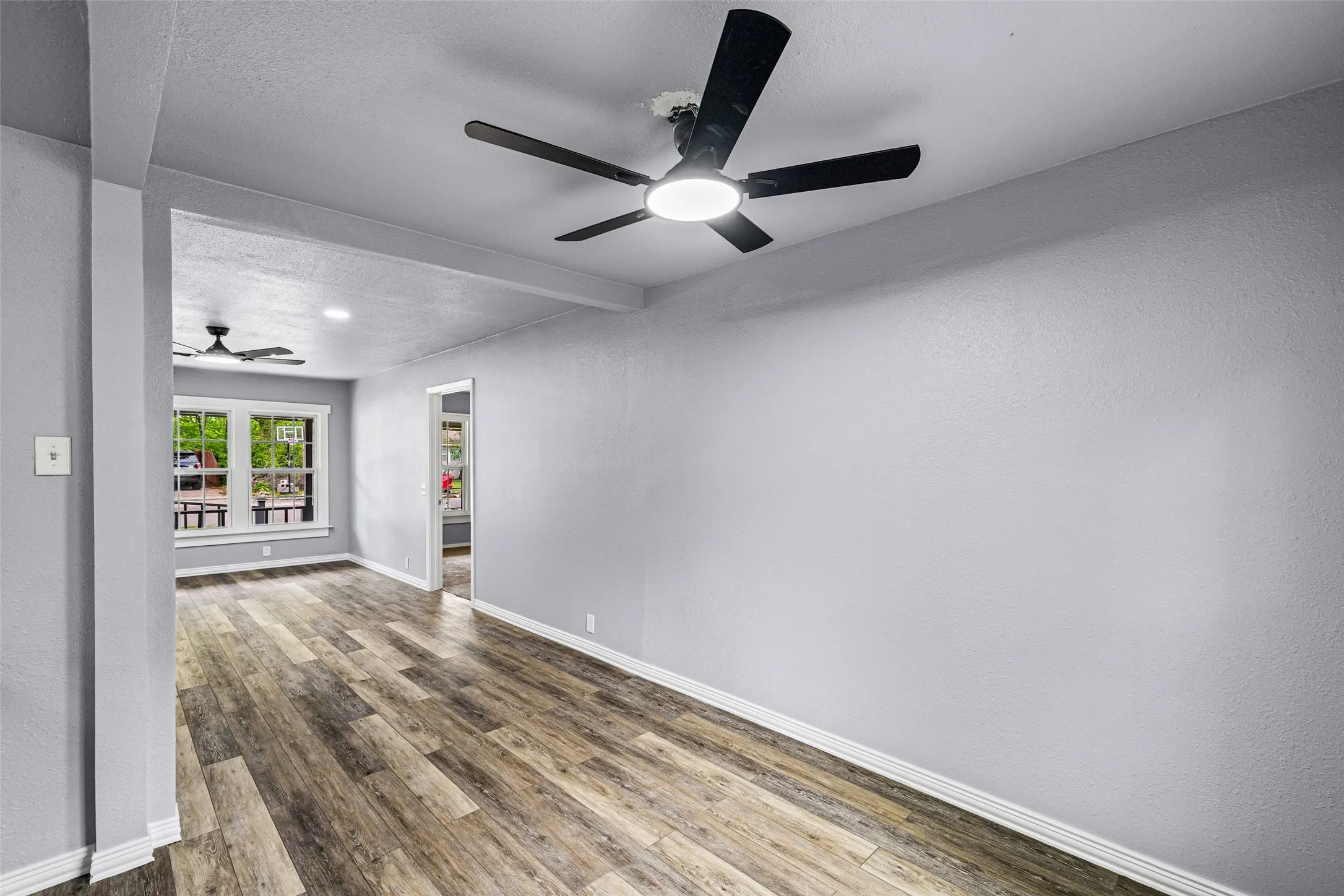 Unfurnished room with a ceiling fan, dark wood finished floors, beam ceiling, a textured ceiling, and a textured wall