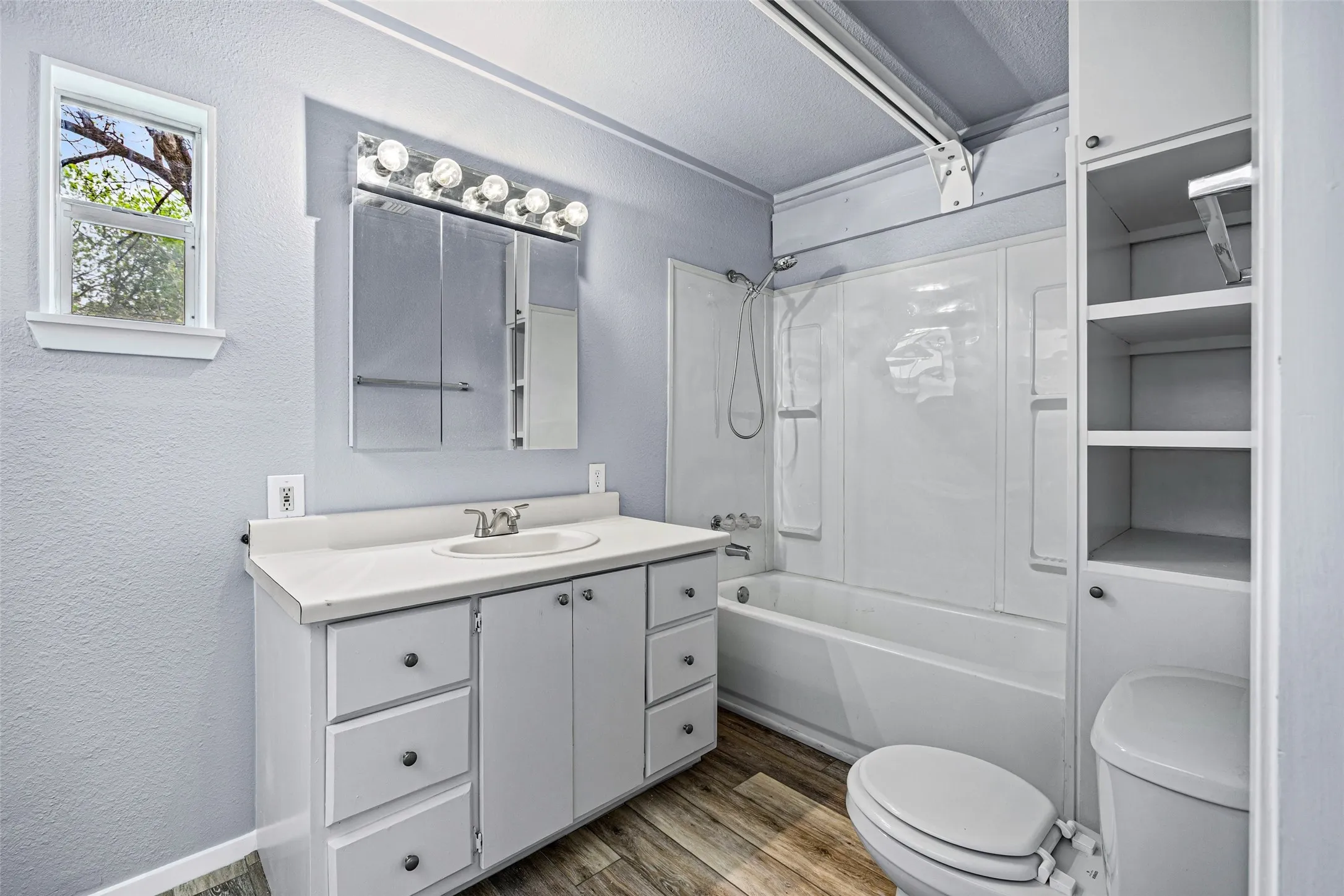 Bathroom featuring a textured wall, vanity, dark wood-style flooring, washtub / shower combination, and a textured ceiling