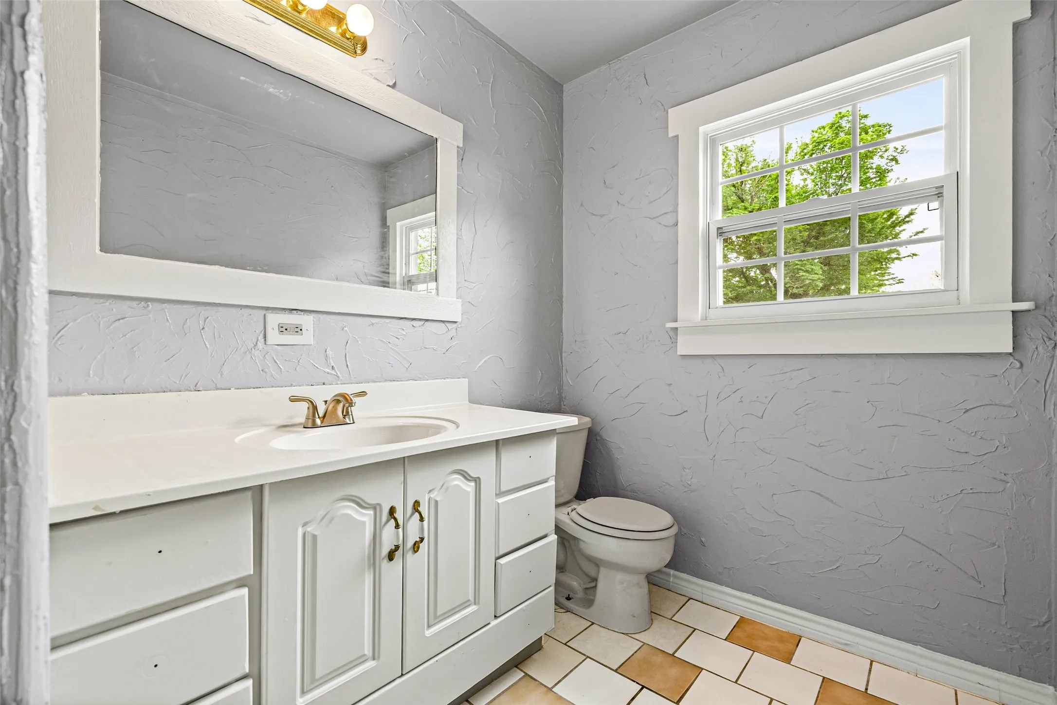 Half bath featuring a textured wall, vanity, and light tile patterned floors