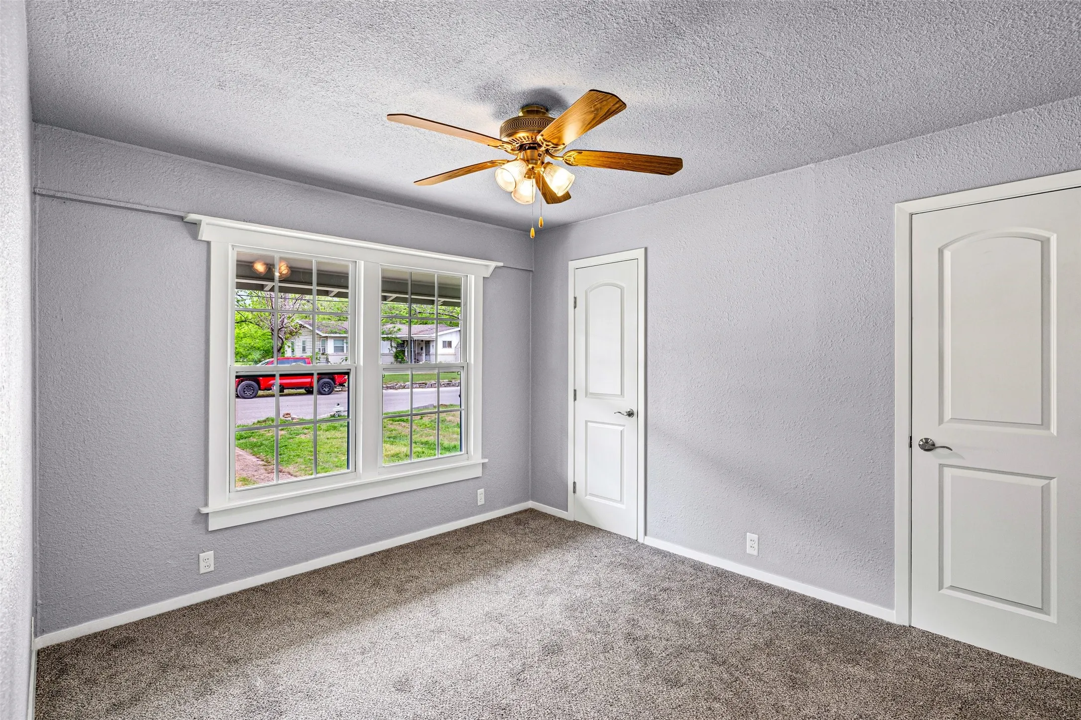 Carpeted spare room featuring a textured wall, a textured ceiling, and ceiling fan