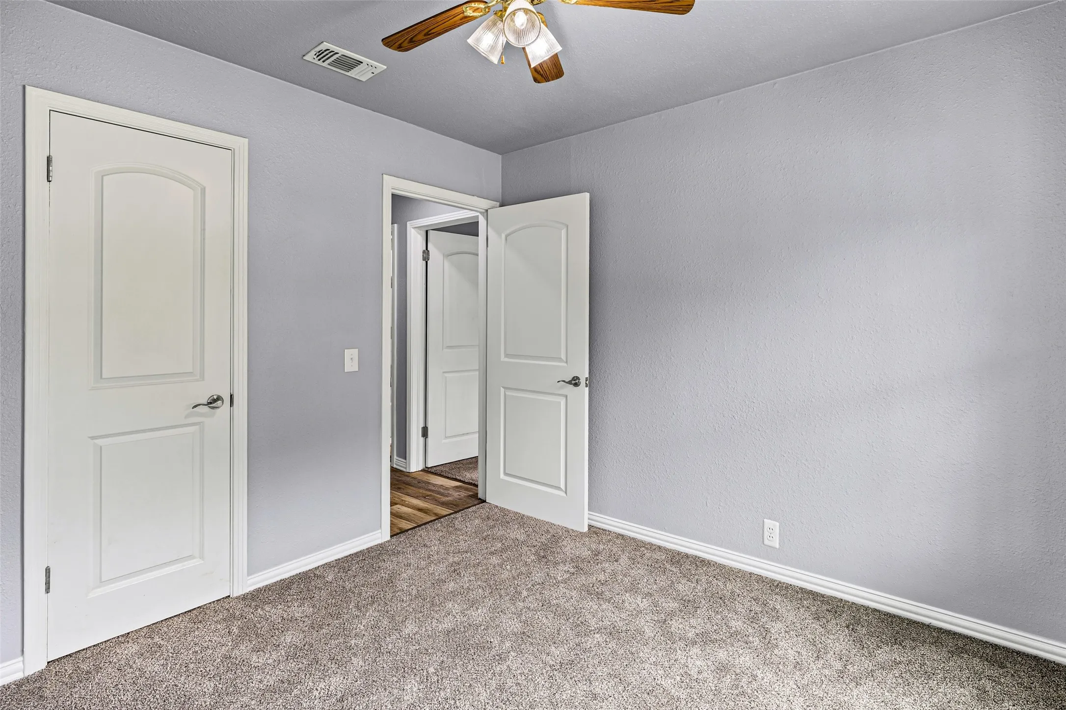 Unfurnished bedroom with carpet, a textured wall, and a ceiling fan