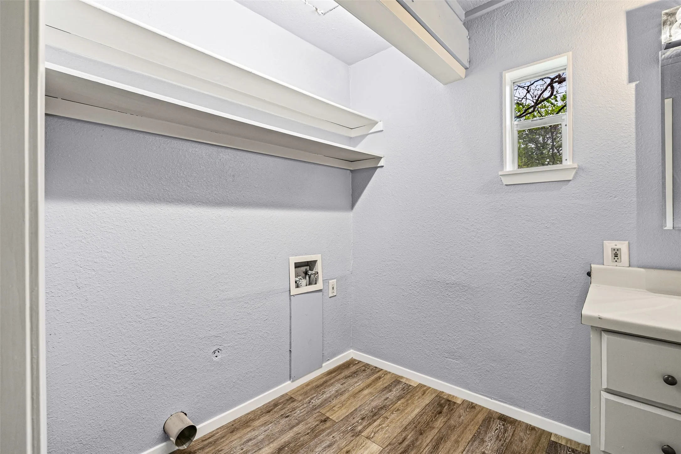 Laundry area featuring a textured wall, wood finished floors, and washer hookup