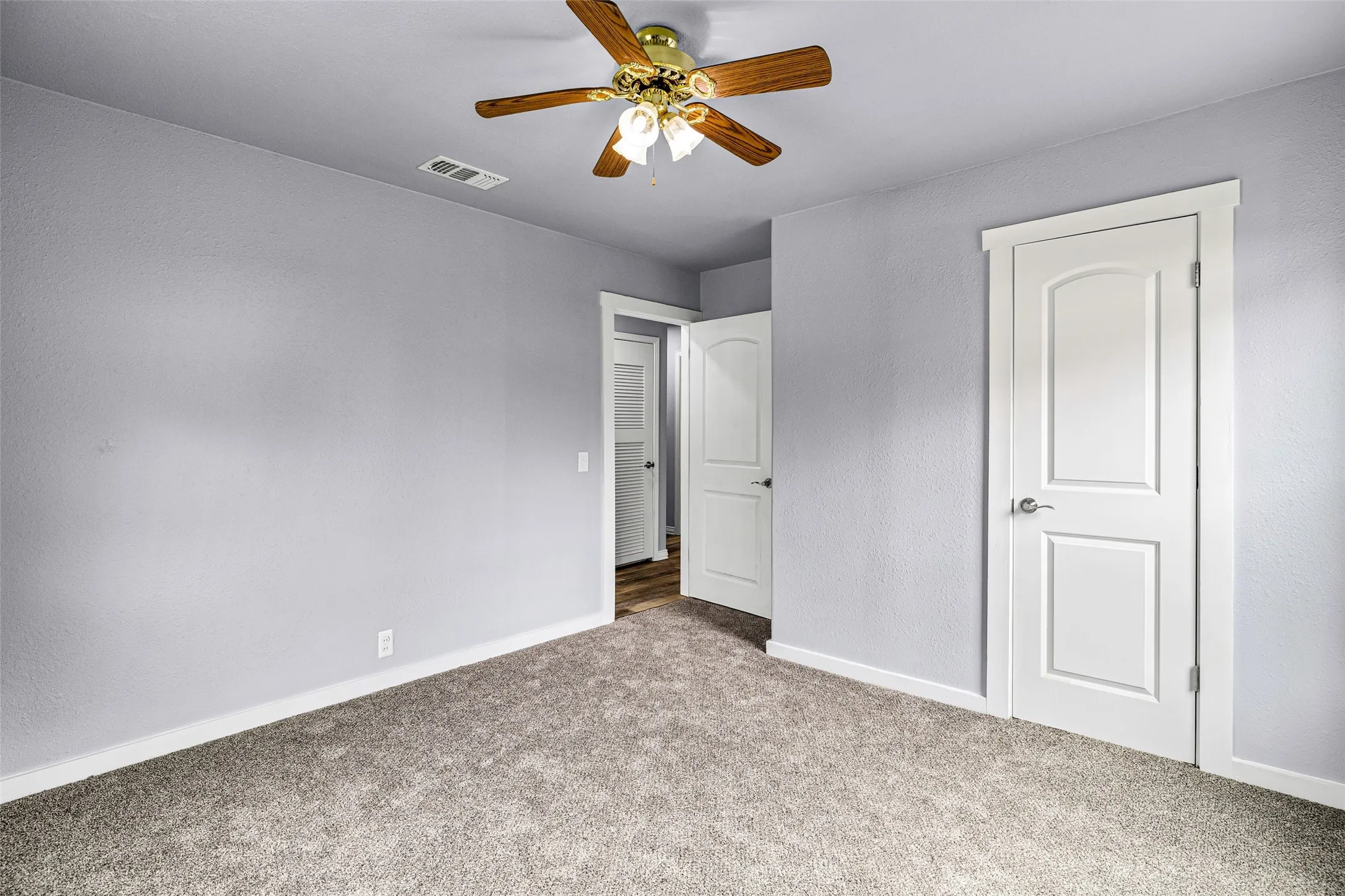 Unfurnished bedroom with carpet flooring, ceiling fan, and a textured wall