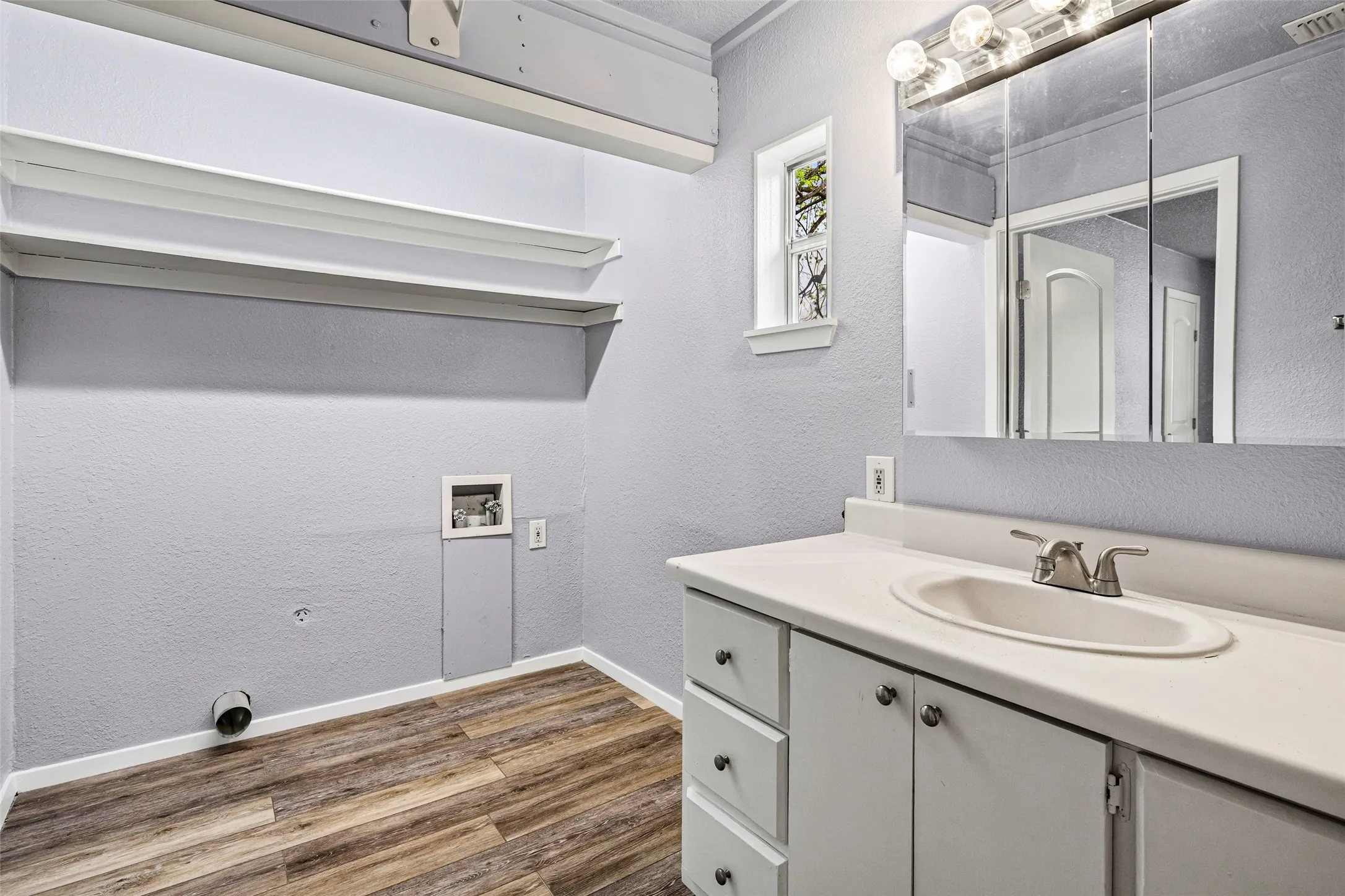 Bathroom featuring a textured wall, vanity, and dark wood-style floors