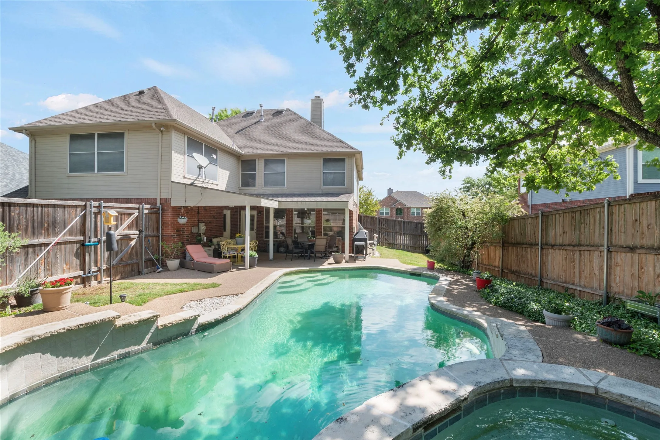 View of swimming pool featuring patio surround, a fenced backyard, an in-ground hot tub, and a gate
