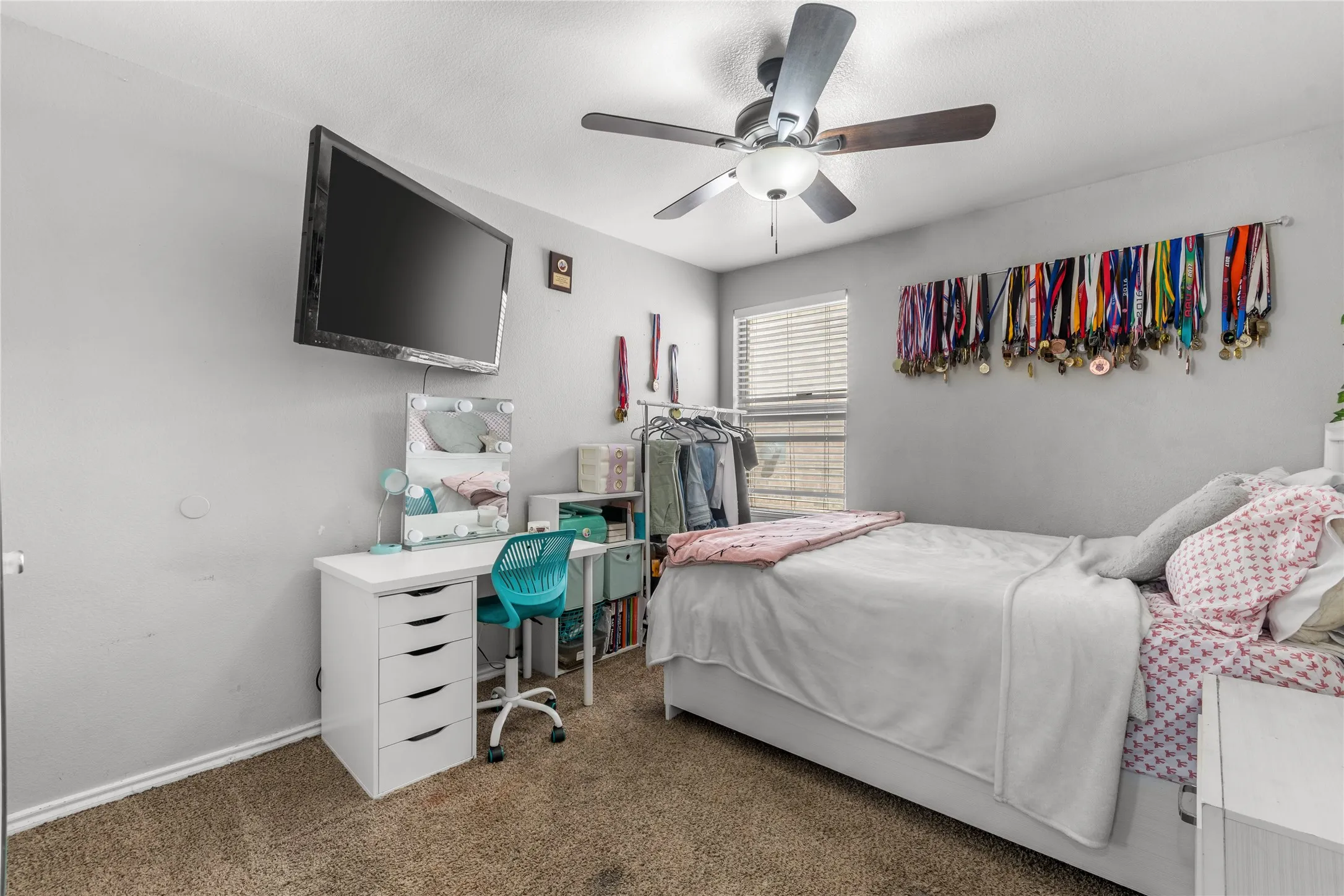 The bedroom features a ceiling fan, a window with horizontal blinds, and carpeted flooring
