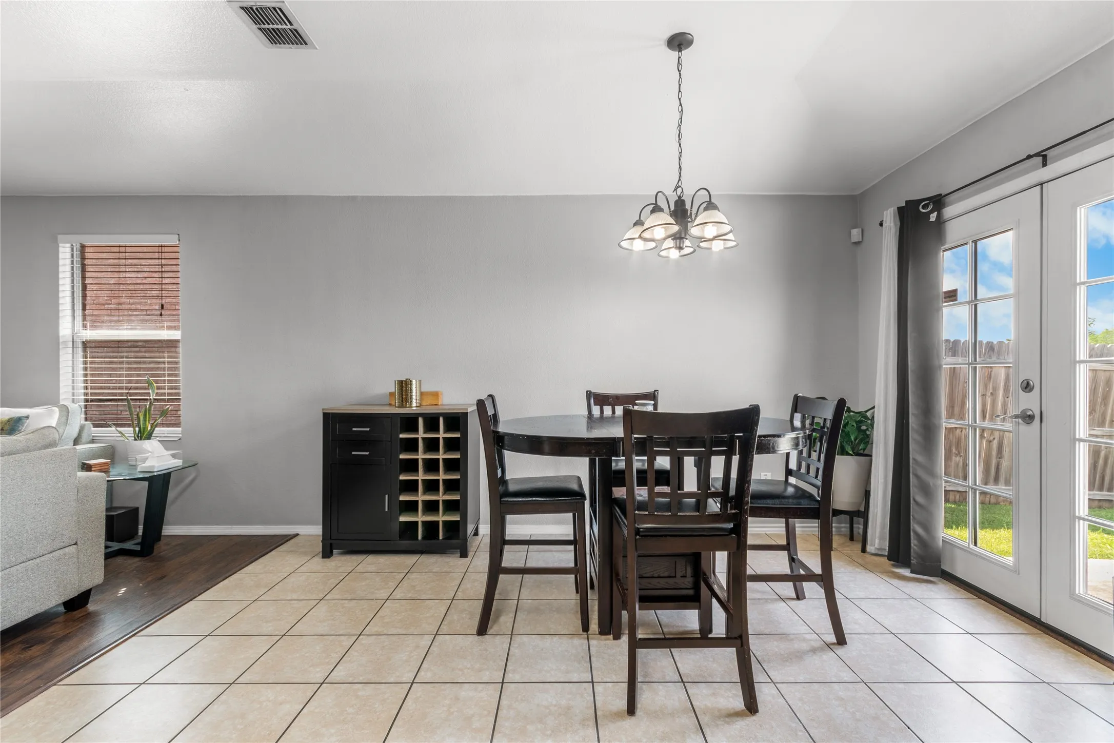 This room features light-colored tile flooring, a window with blinds, and French doors providing access to the​​‌​​​​‌​​‌‌​‌‌​​​‌‌​‌​‌​‌​​​‌​​ outdoors