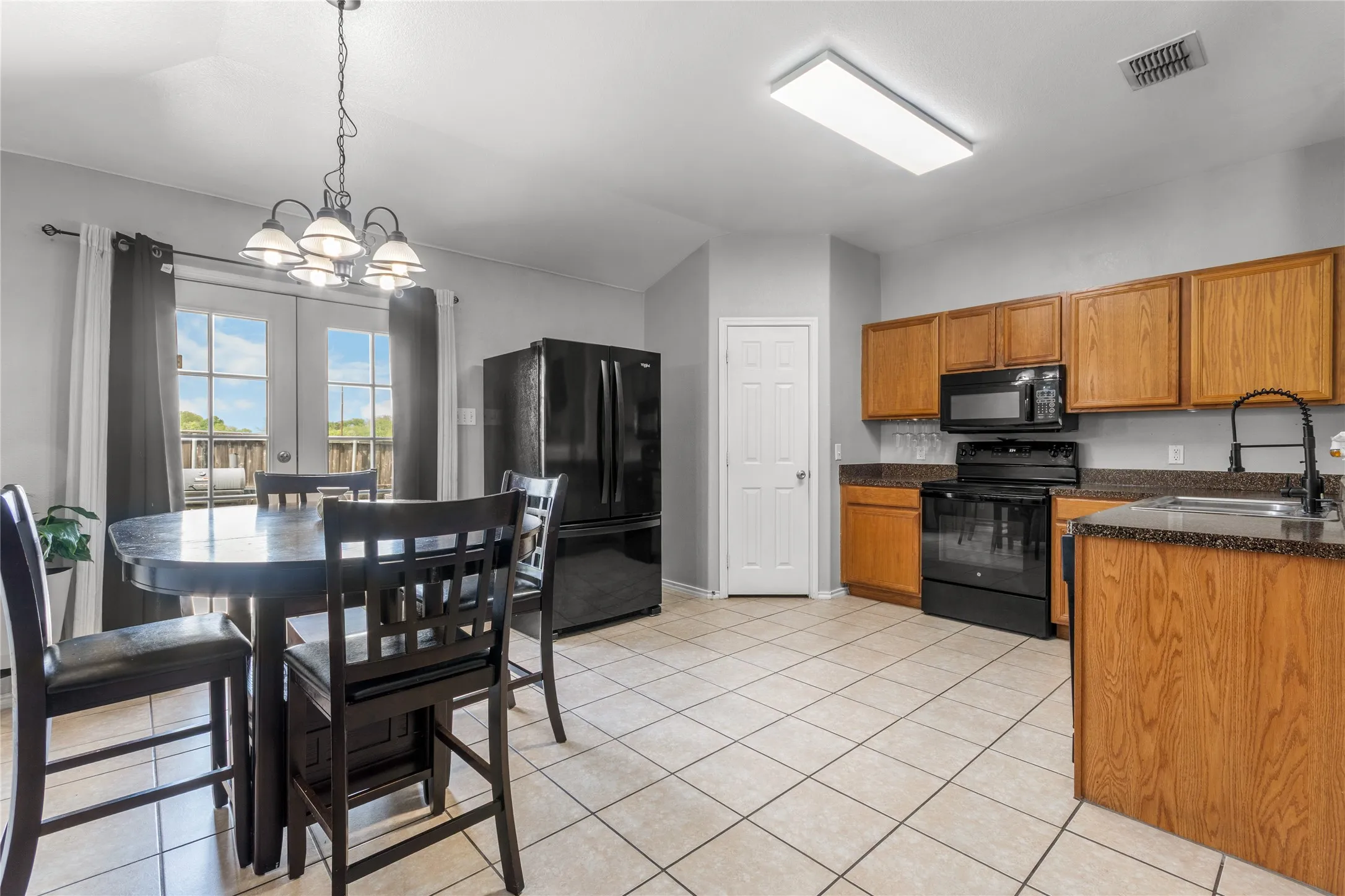 The kitchen features wood cabinetry, dark countertops, and black appliances