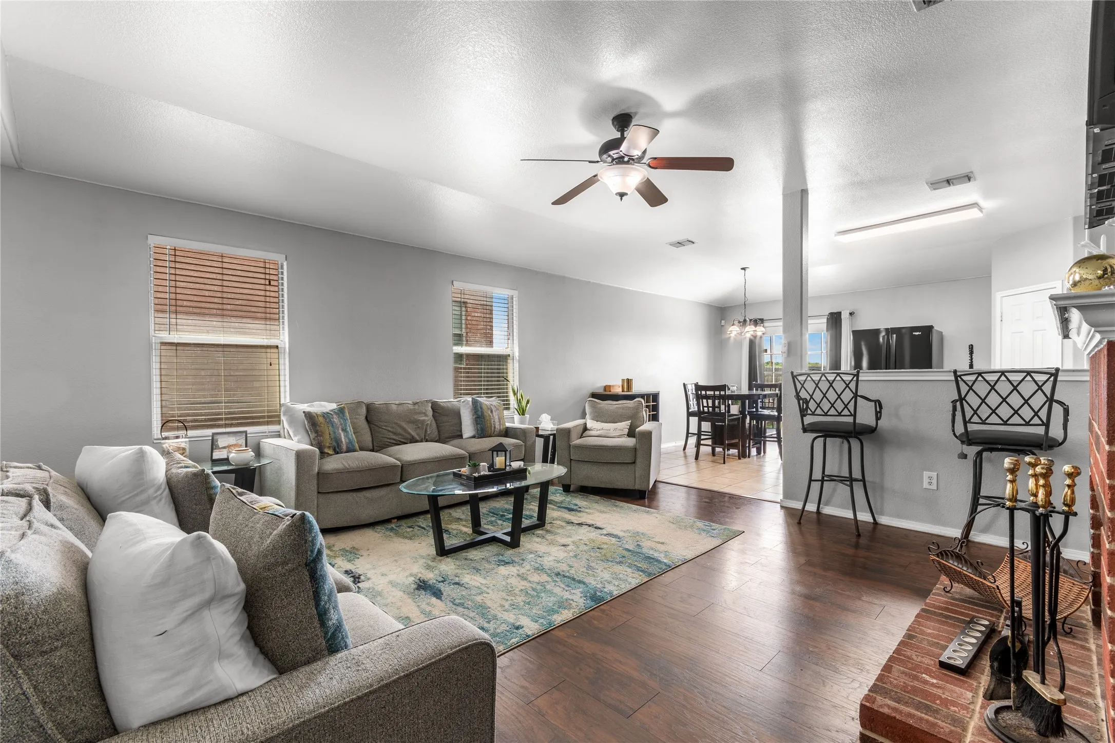 The living area features wood flooring, a ceiling fan, and a brick fireplace