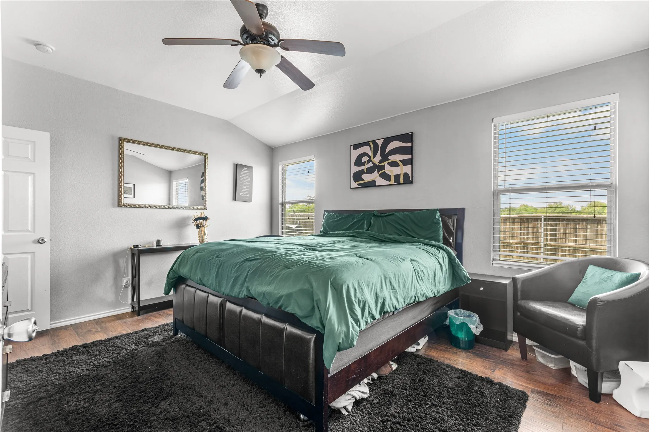 This room features vaulted ceilings, a ceiling fan, and rich wood-style flooring