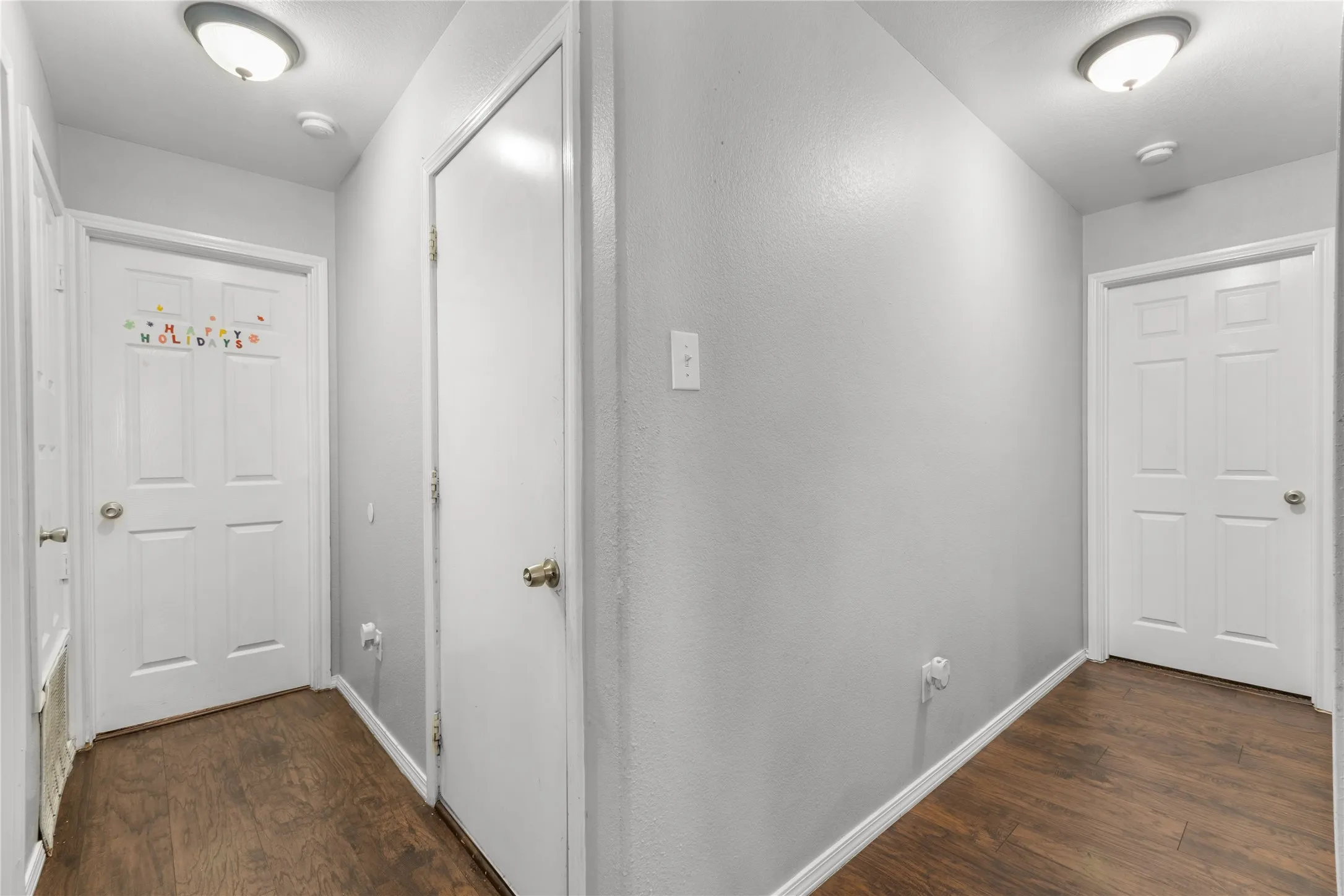 Hallway featuring hardwood style flooring, light gray walls, and white doors