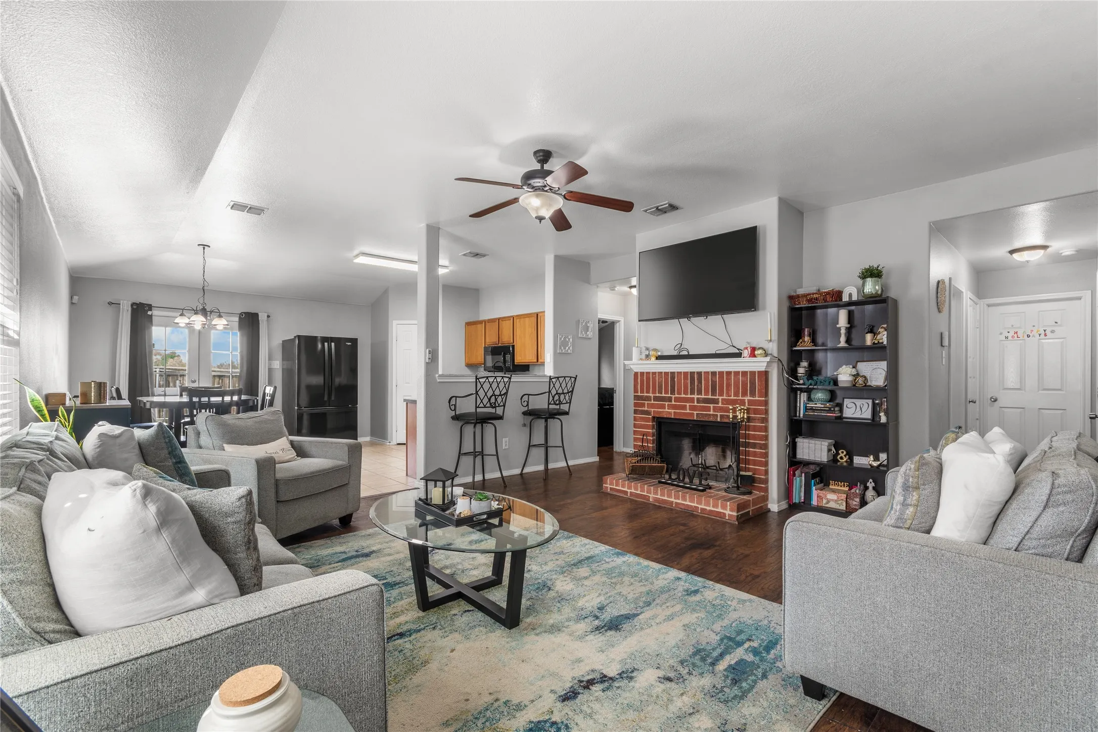 The living area features hardwood floors, a brick fireplace, and a ceiling fan