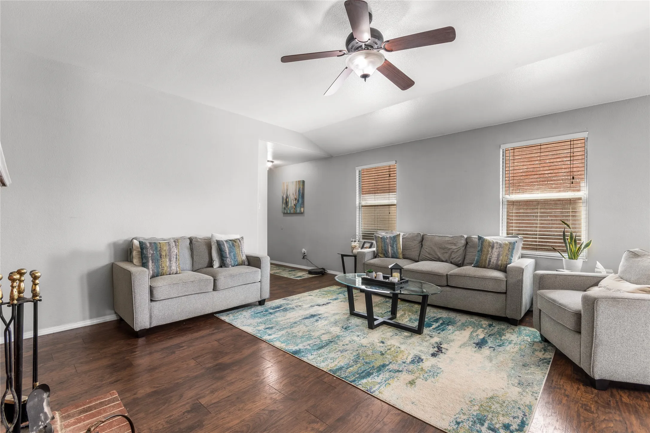 Living area featuring hardwood flooring, light-colored walls, and a ceiling fan
