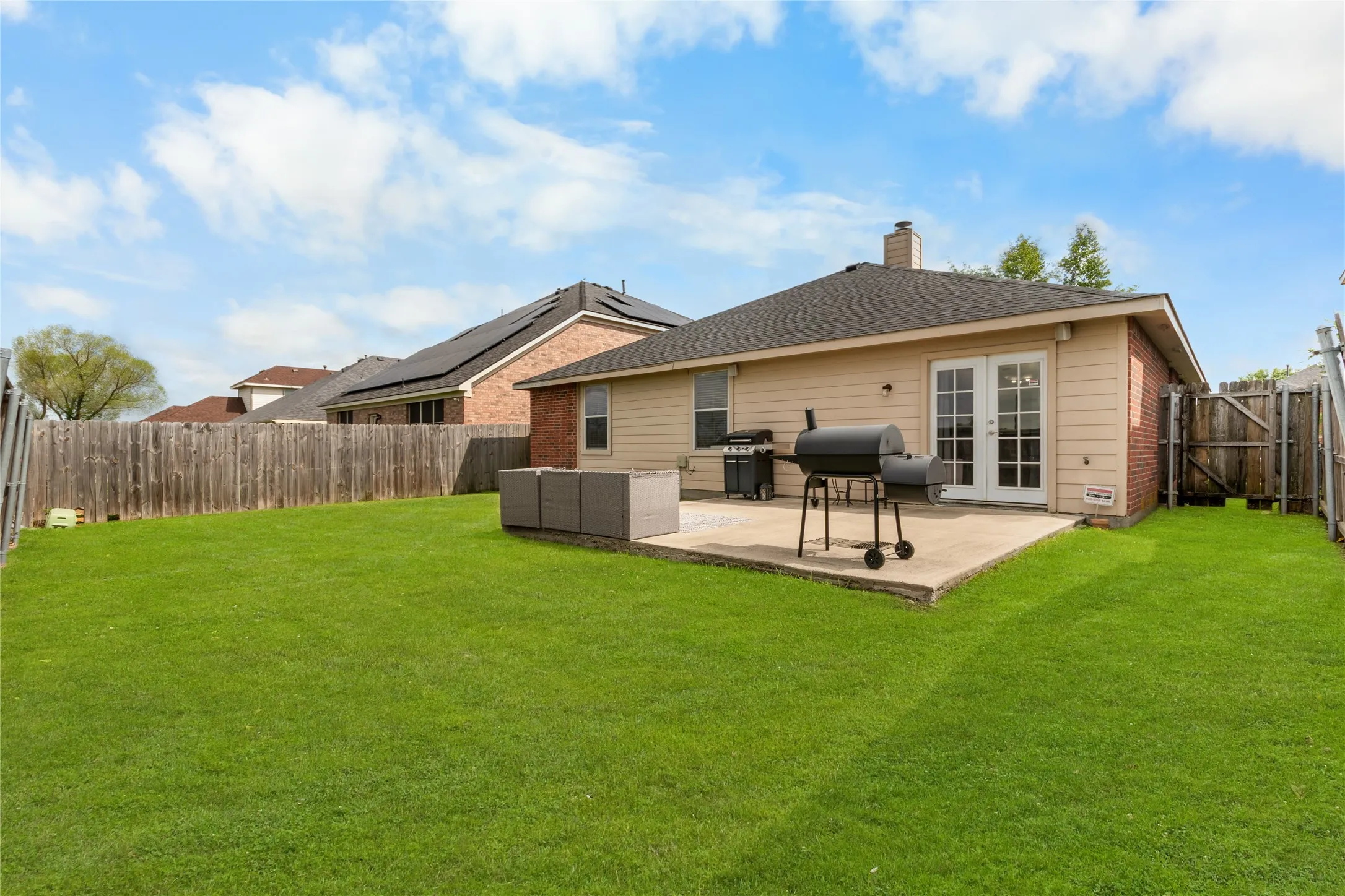 The property features a spacious backyard with a well-maintained lawn and a private wooden fence. Enhanced Grass