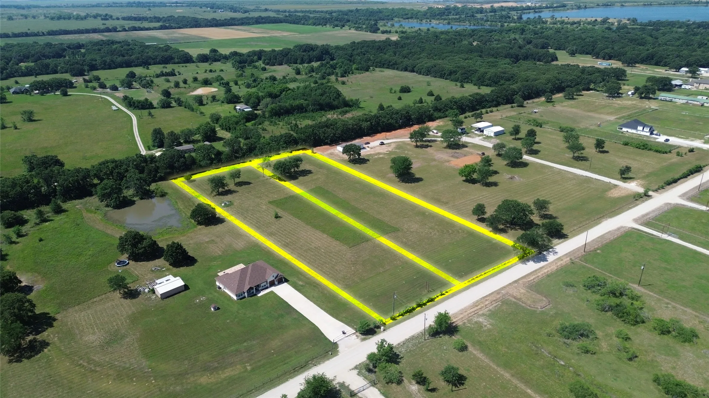 Expansive land parcel featuring multiple delineated lots, mature tree cover, and a water feature