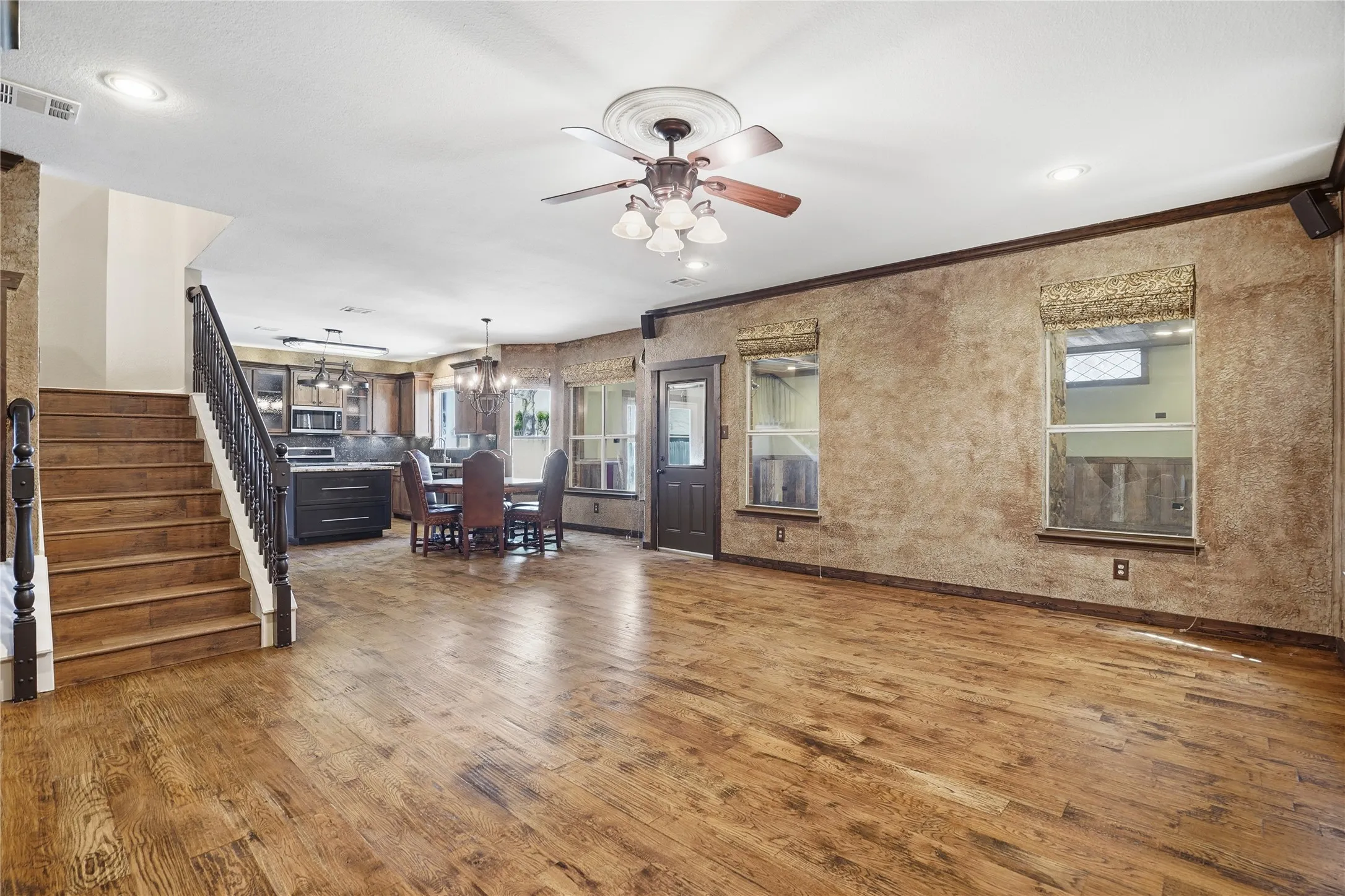 Living area featuring dark wood finished floors, a ceiling fan, a chandelier, and crown molding
