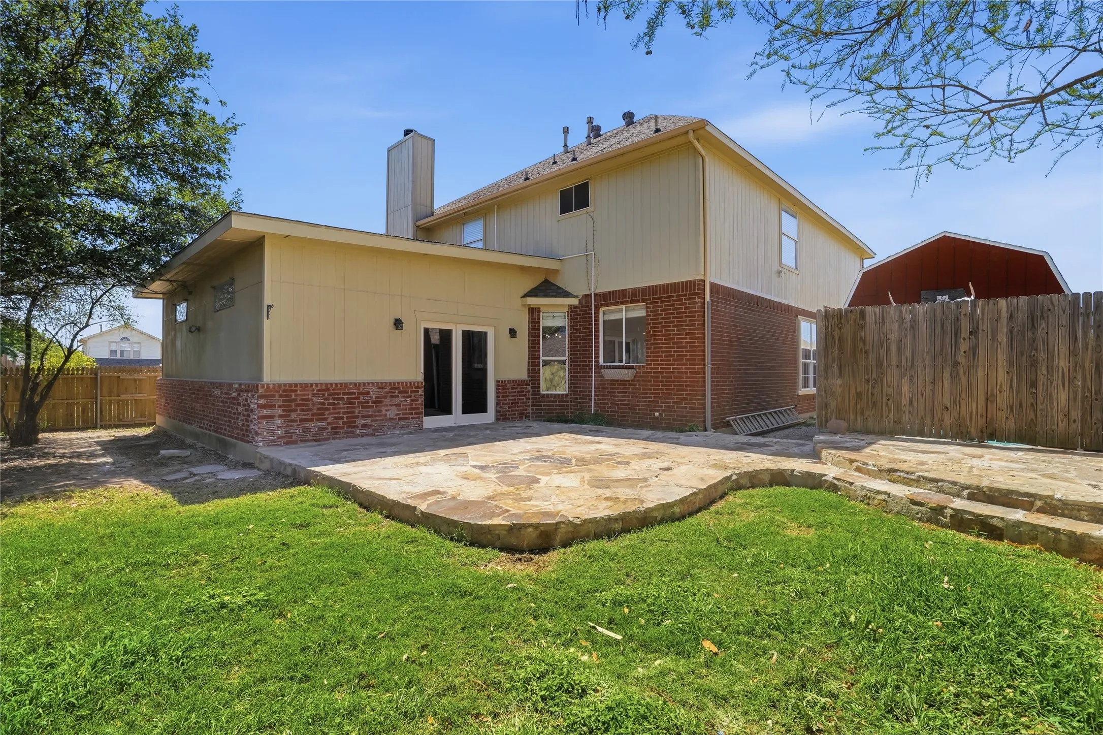 Rear view of house featuring a patio, brick siding, a fenced backyard, and a chimney