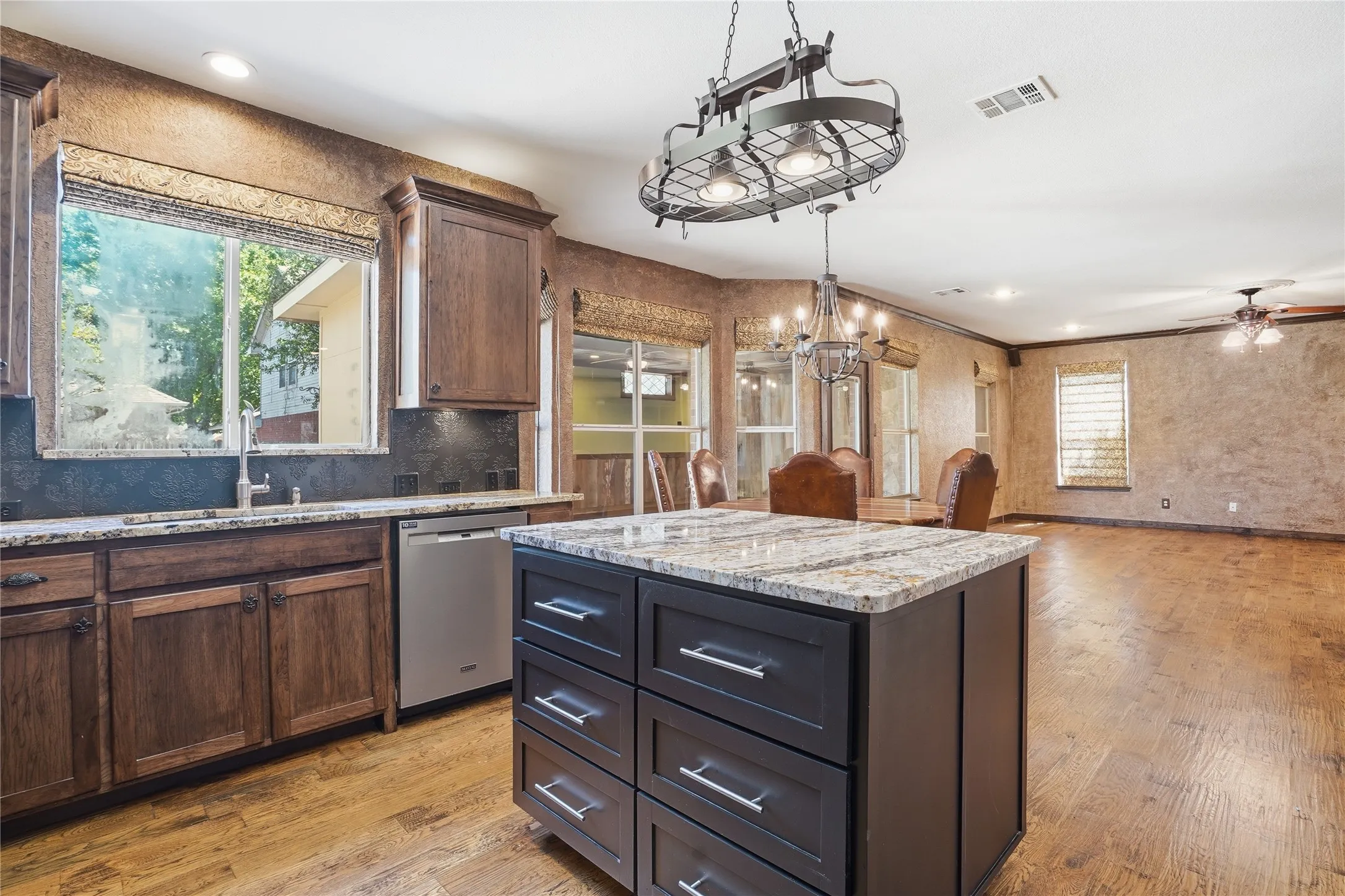 Kitchen featuring a kitchen island, light wood-type flooring, light stone countertops, open floor plan, and dishwasher