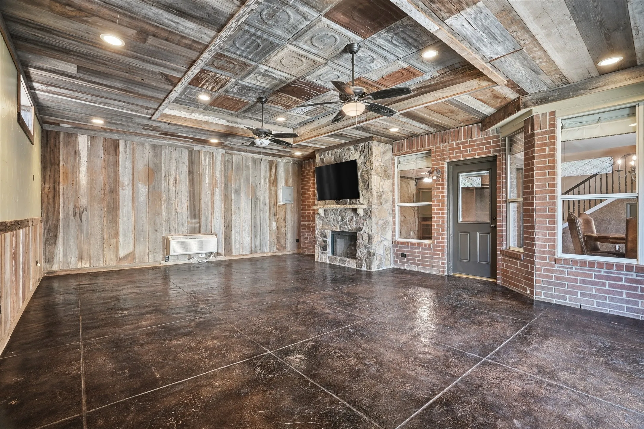 Unfurnished living room featuring wood walls, a fireplace, and a ceiling fan
