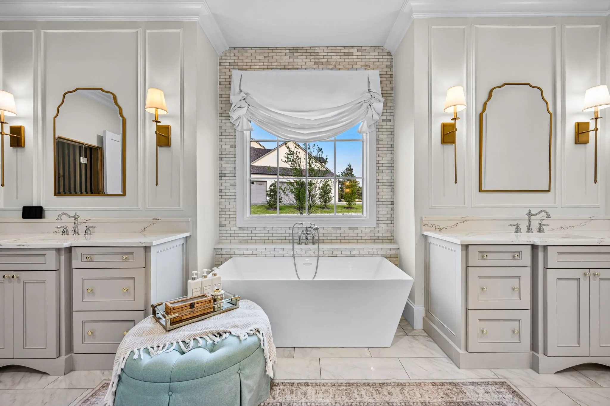 Elegant his and her vanities book end this picture window and pedestal tub with beautifully done tile wall backdrop