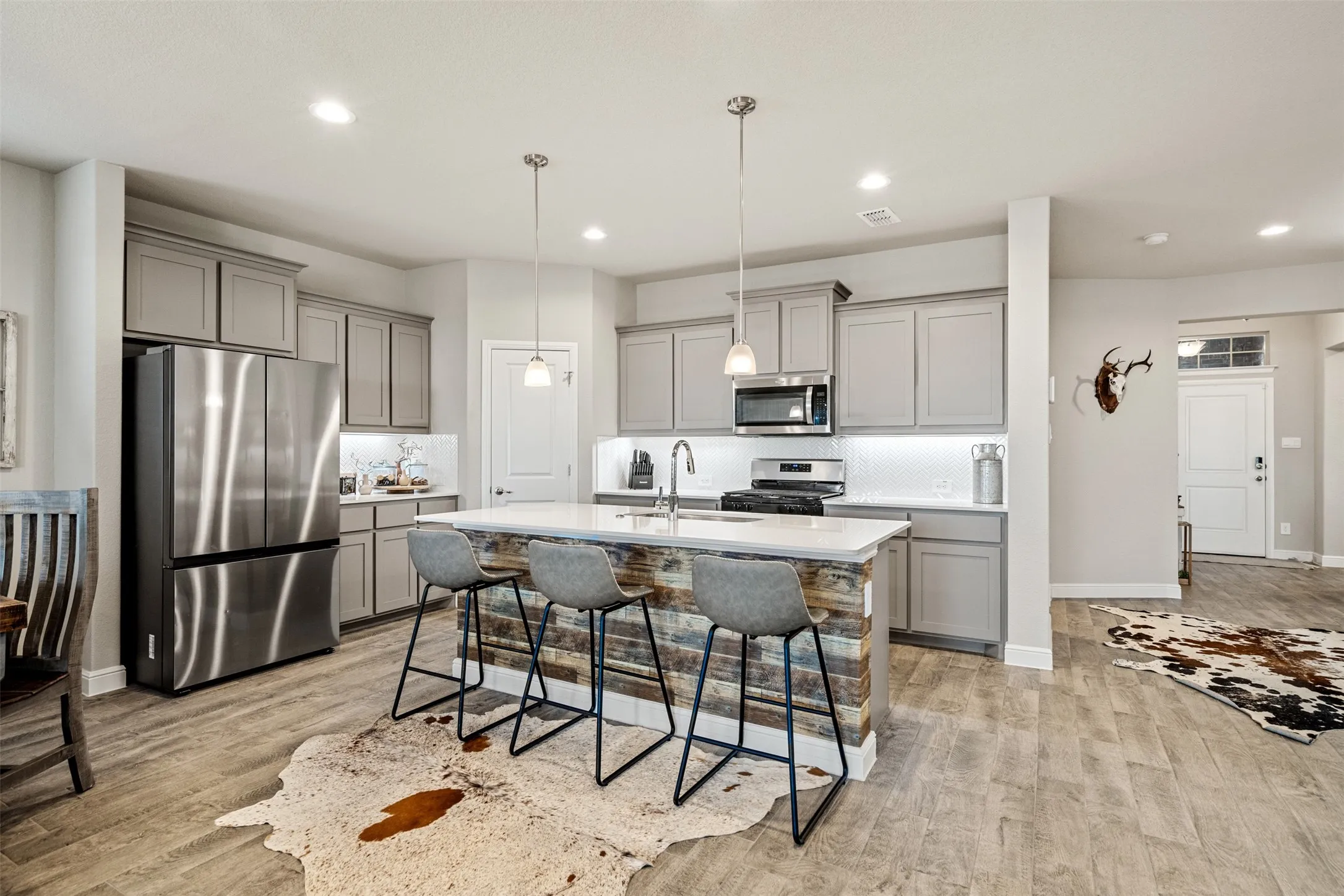 Kitchen featuring gray cabinets, stainless steel appliances, a breakfast bar, and tasteful backsplash