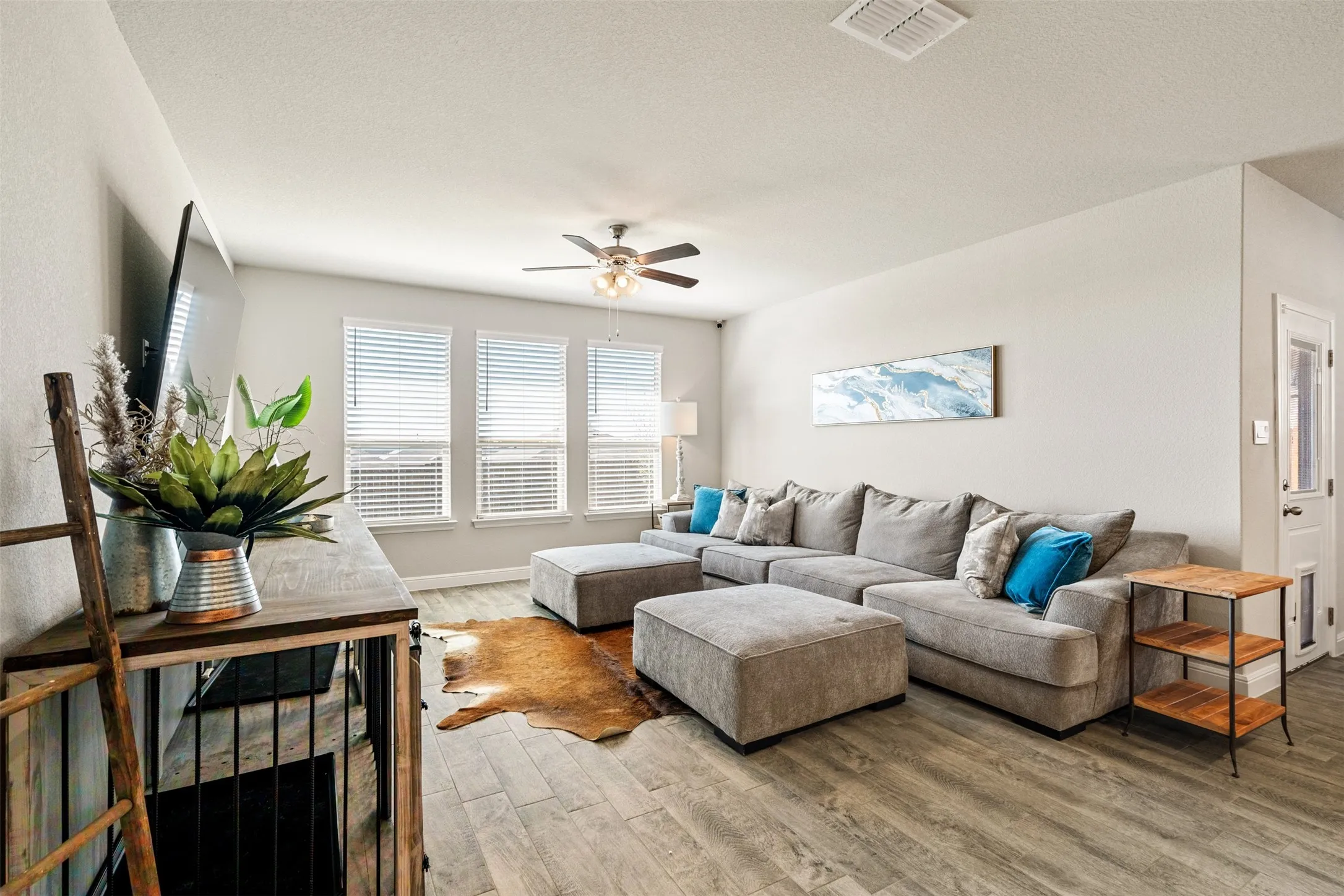 Living room with ceiling fan, light wood finished floors, and a textured ceiling