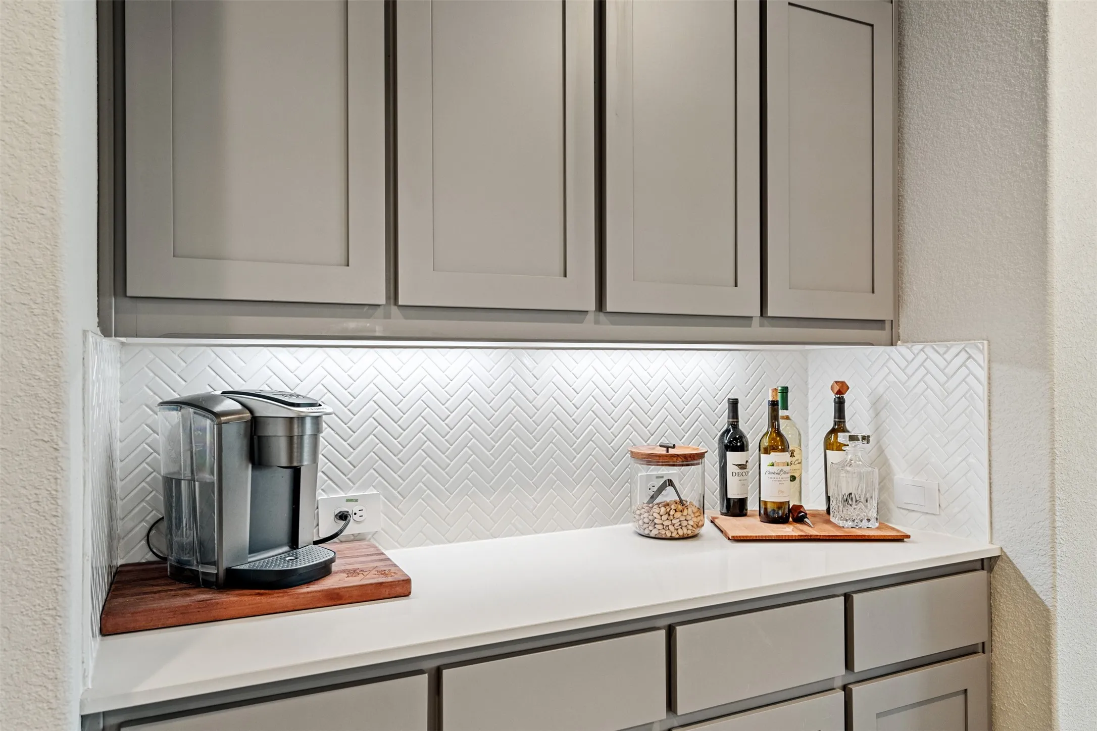 Bar featuring a textured wall, gray cabinetry, and backsplash