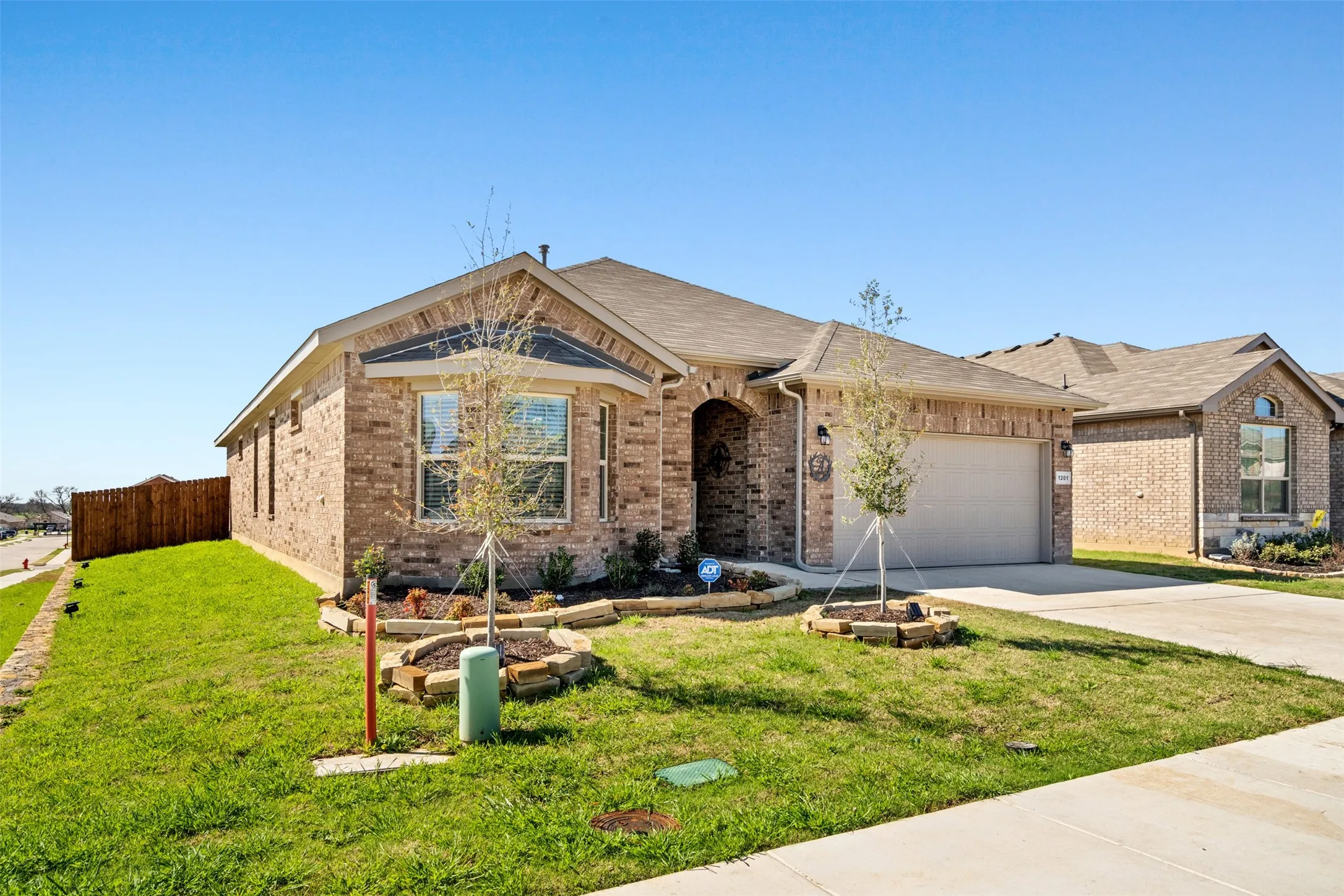 Single story home featuring an attached garage, concrete driveway, and brick siding